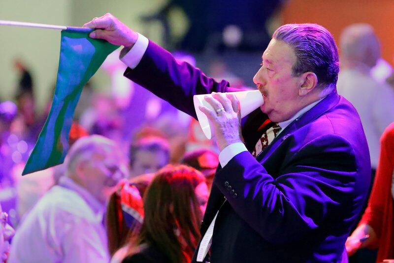 A man in a suit holds a megaphone and signals directions in the middle of a crowd