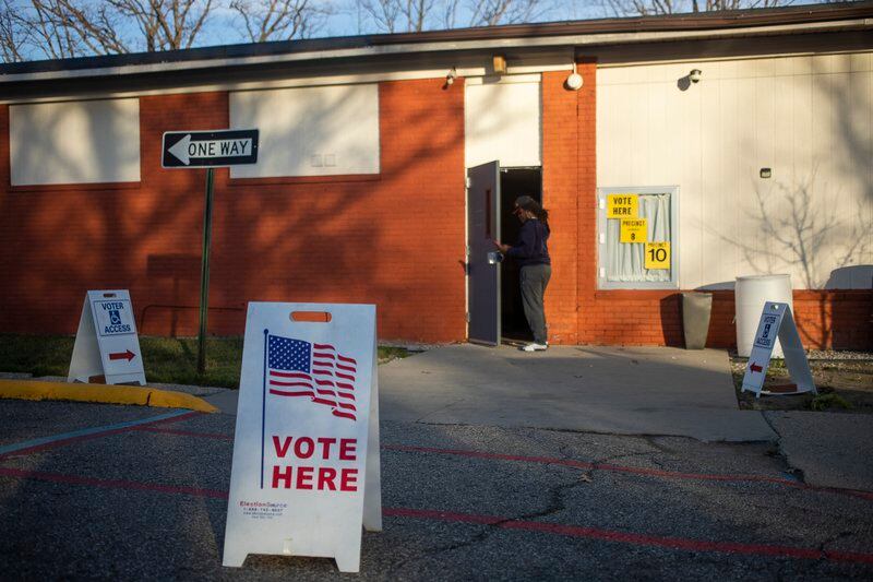 A polling place is lit by golden hour light, with a sign out front that reads “Vote Here”.