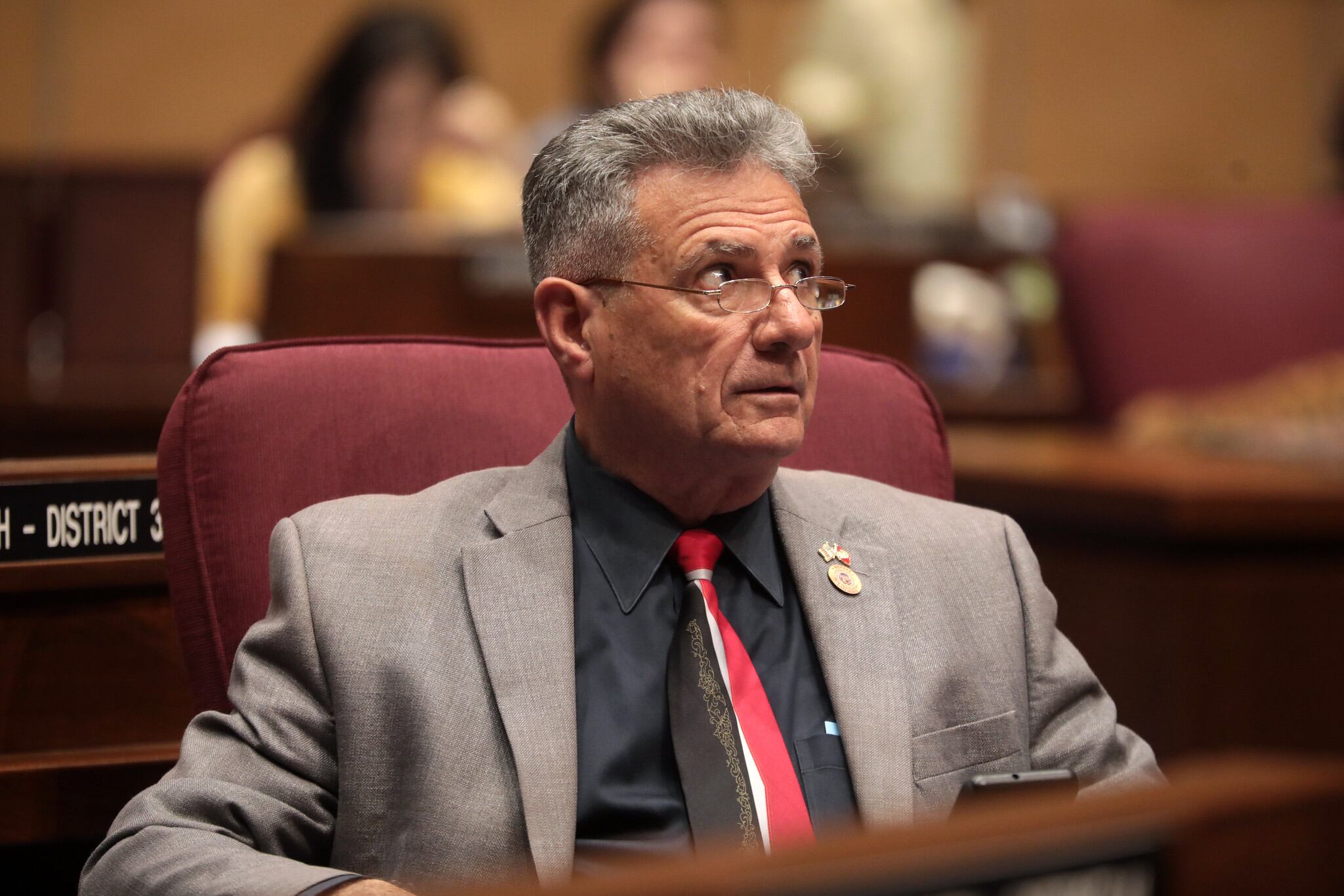 A man in a suit seated at a table looking upward