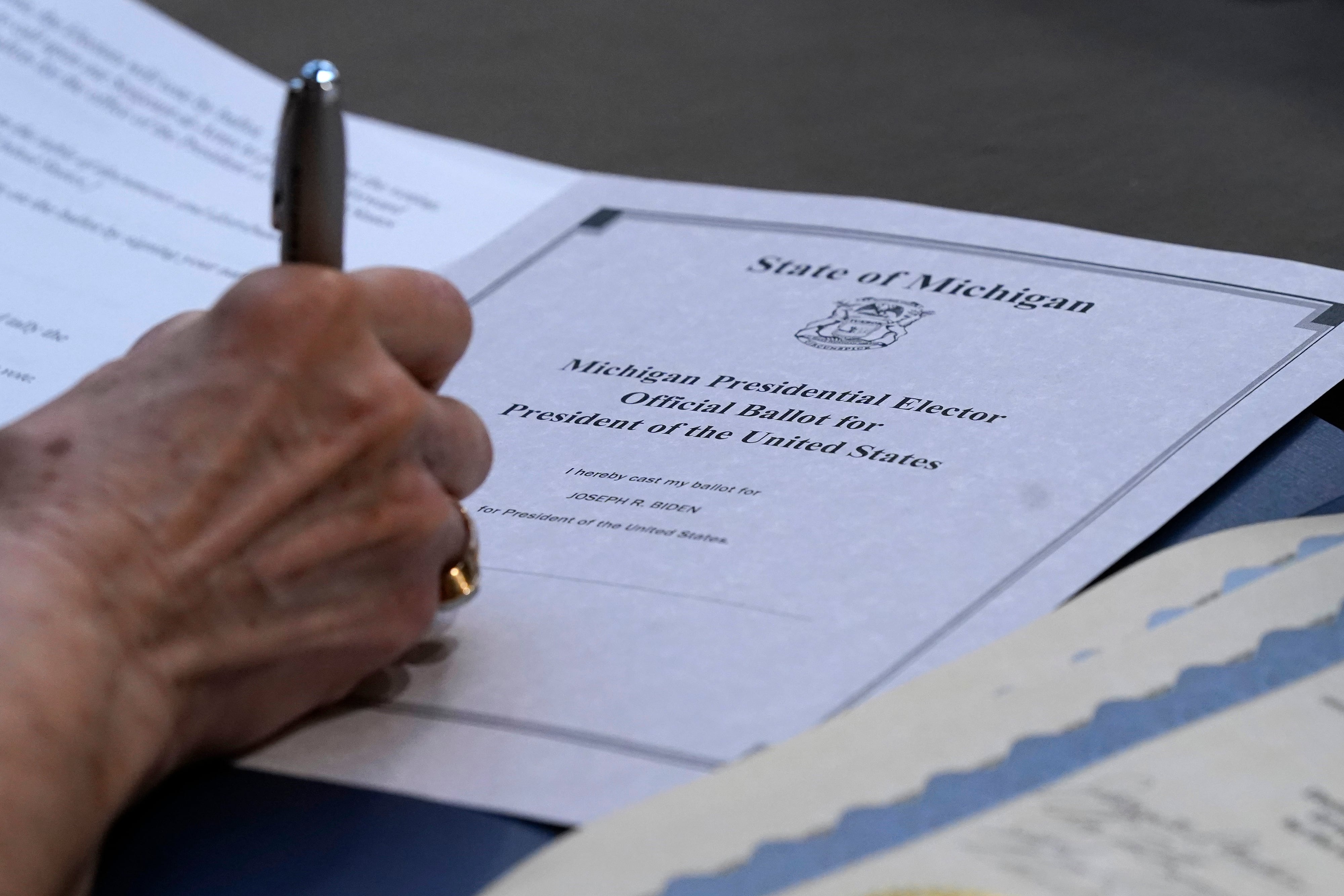 A close up image of a hand writing on an official election document.