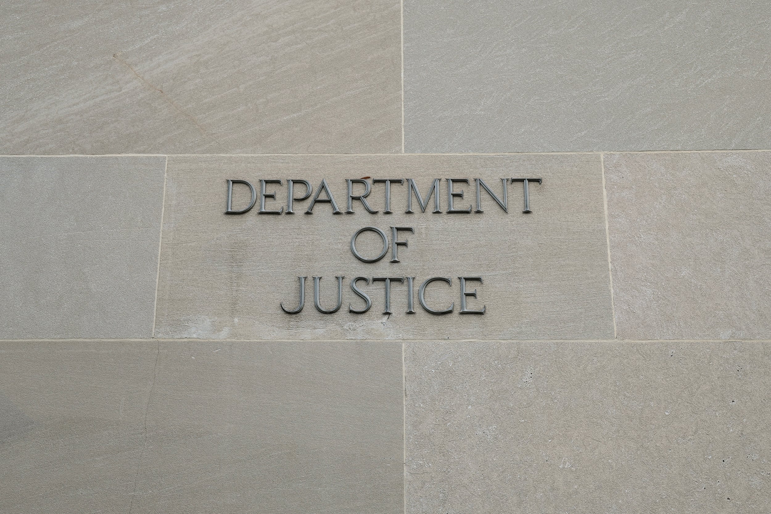 Side of the stone U.S. Department of Justice Building with words carved into the side of the building that reads "Department of Justice."