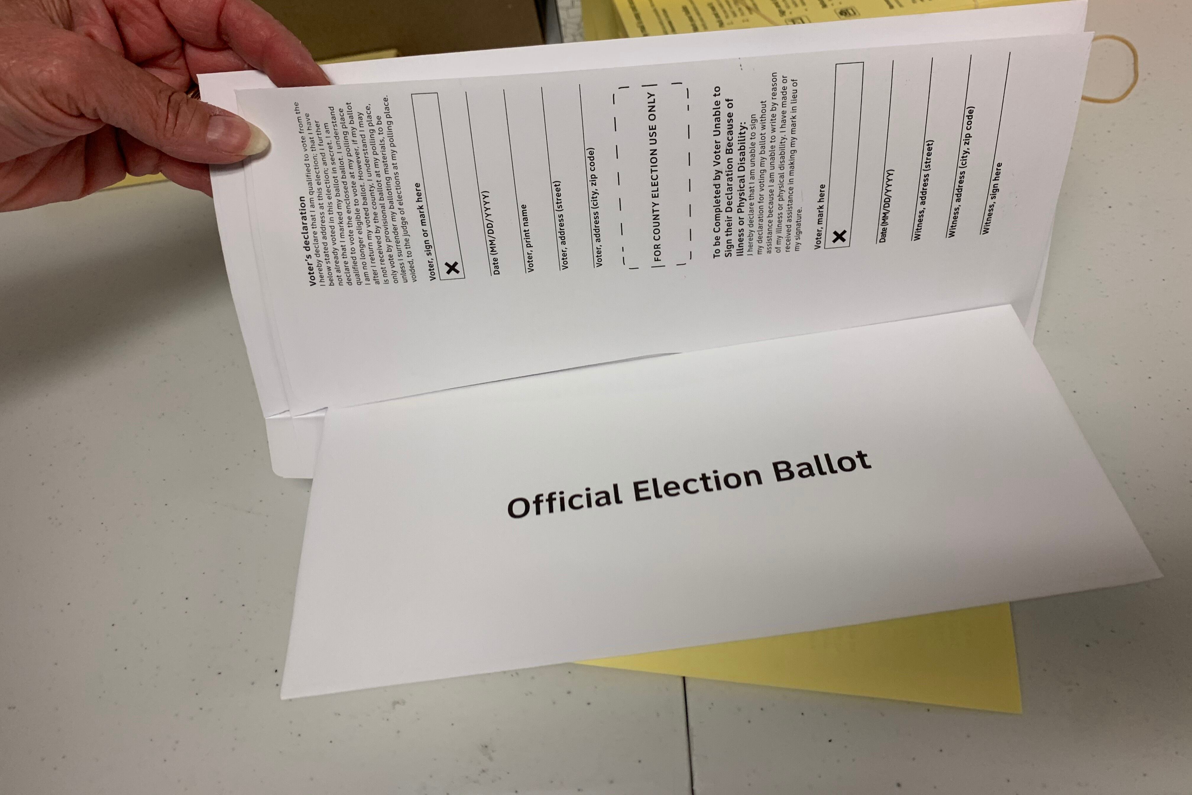 One hand holds up a white piece of paper.
