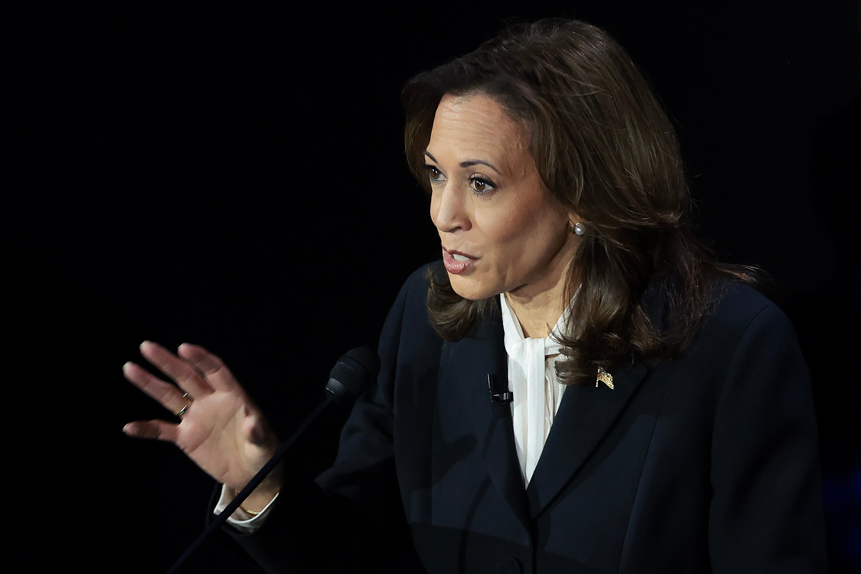 Kamala Harris in a dark suit gestures while looking to her right.