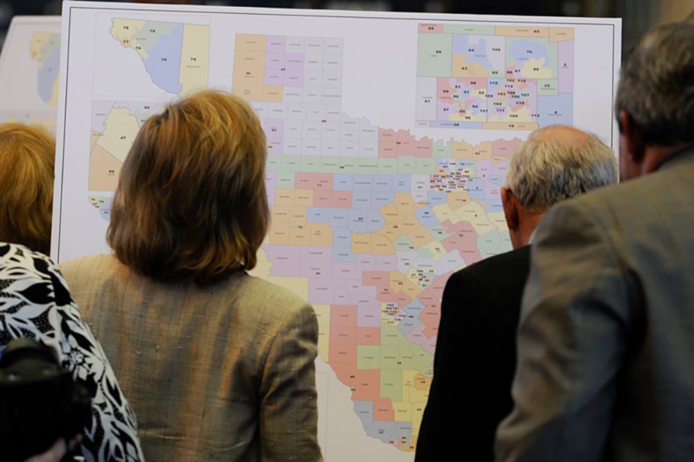 A photograph of three people looking at a map of Texas.