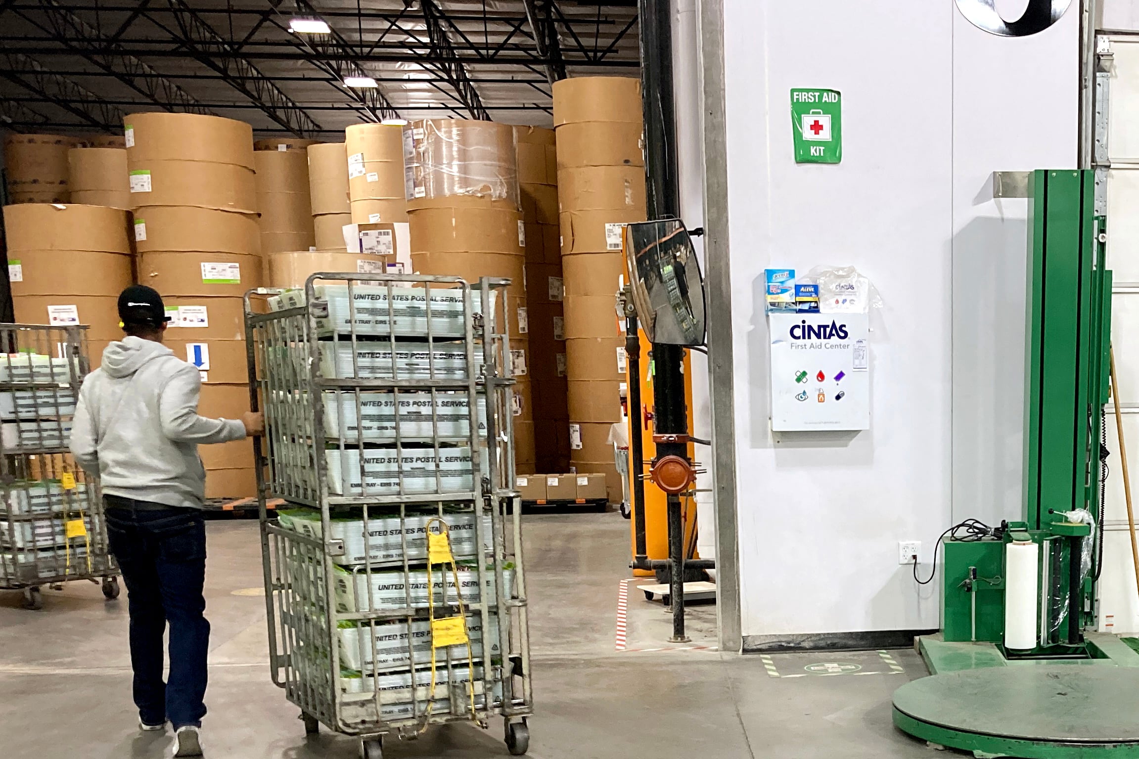 A person rolls a cart full of ballot boxes in a warehouse.