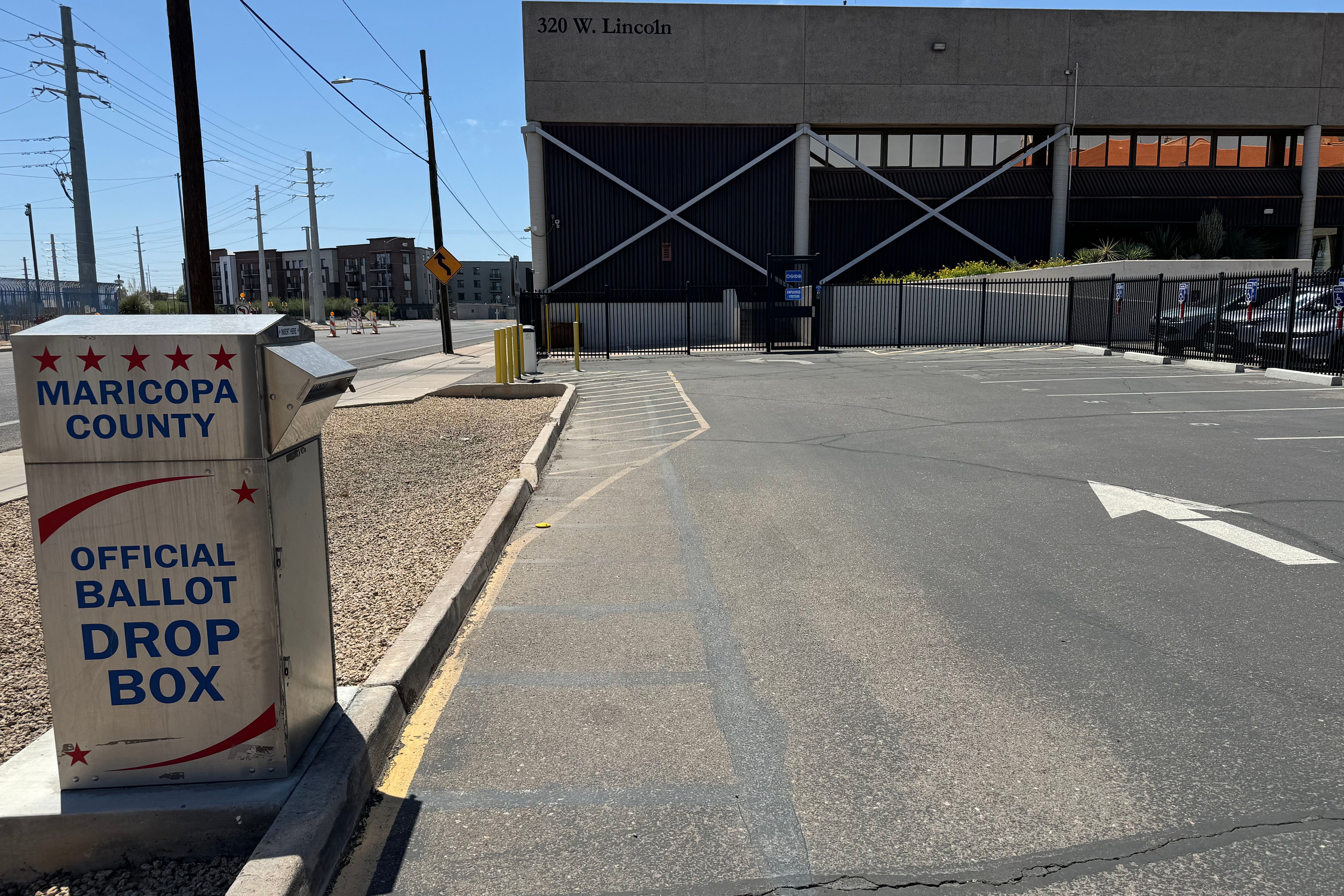 A ballot drop box outside the Maricopa Count election center building with a concrete road in the foreground.