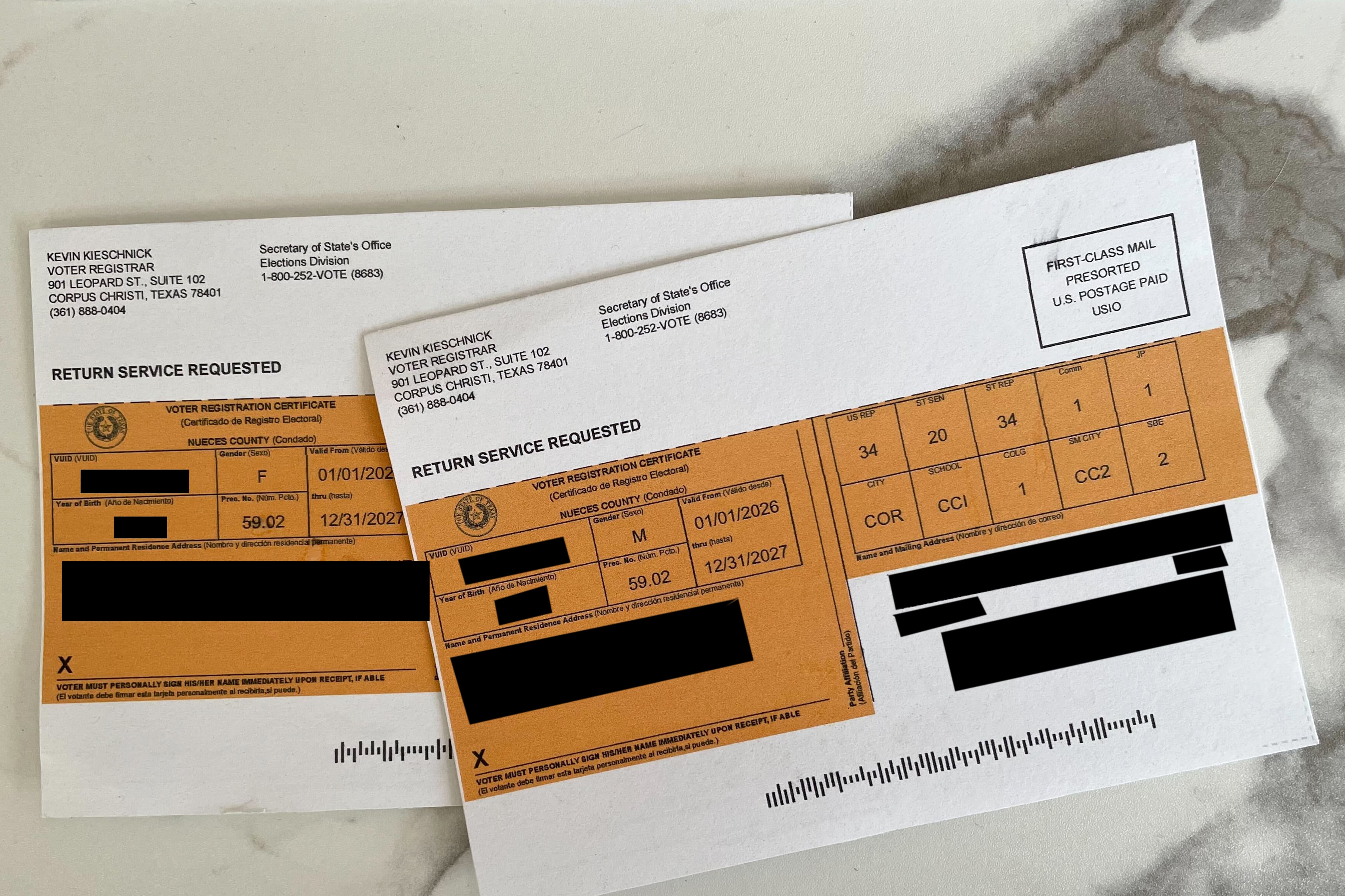 A photograph of two white and orange cards sitting on a marble countertop.