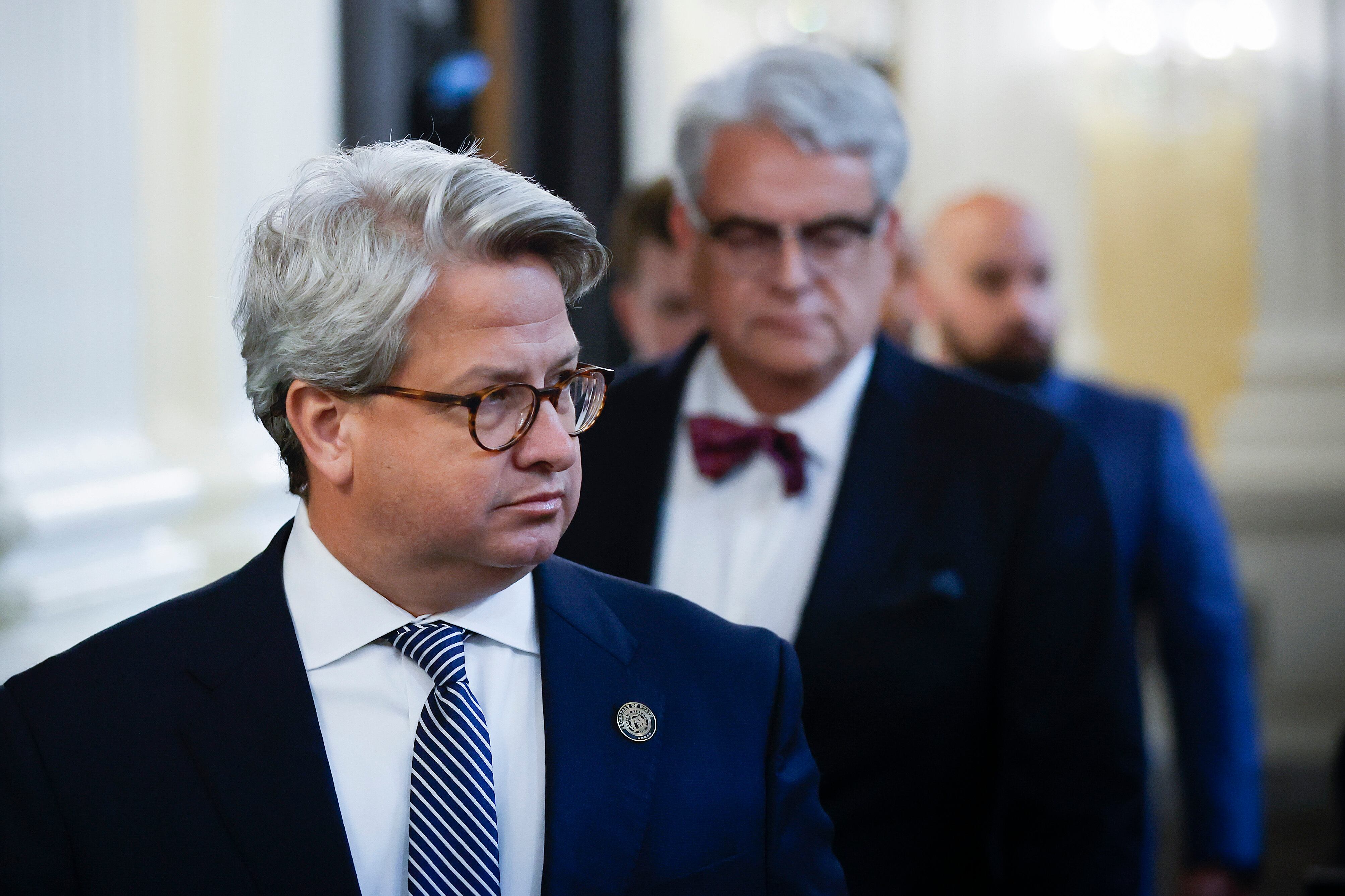 Gabriel Sterling walks to the January 6th hearing, wearing a blue suit jacket, tie, and glasses.