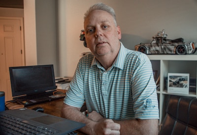 A man in a light blue shirt poses for a portrait in a house.