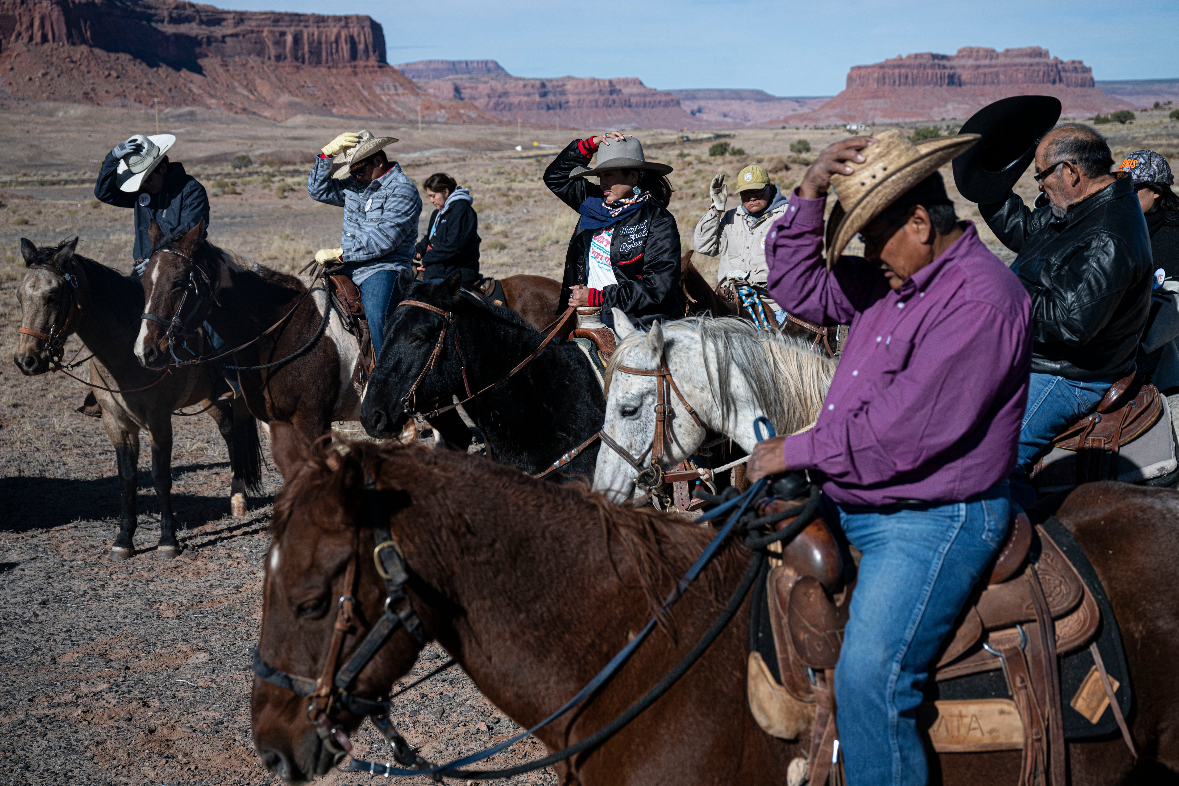 People wearing cowboy hats ride horses.