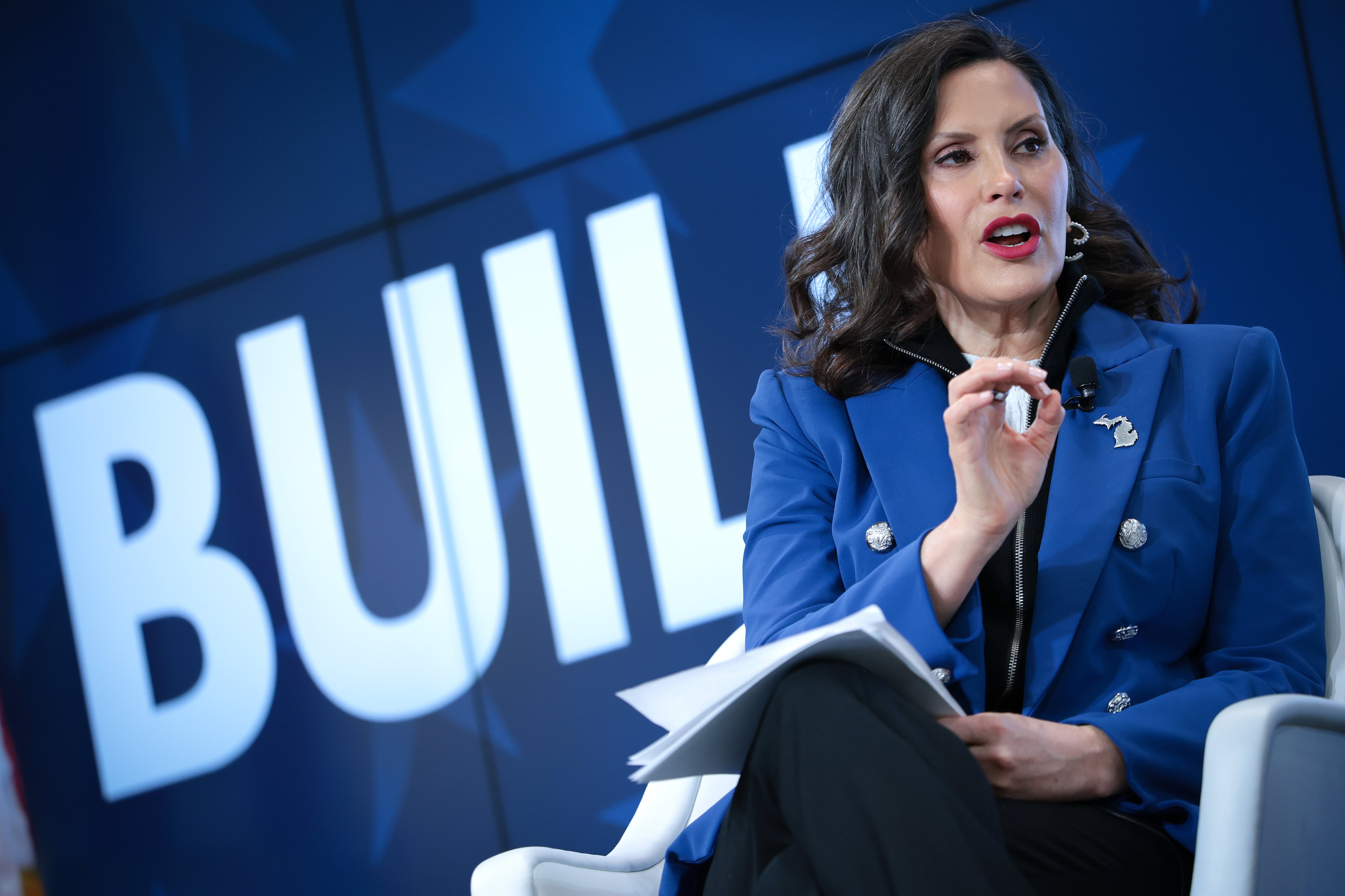 A woman in a blue suit jacket speaks.