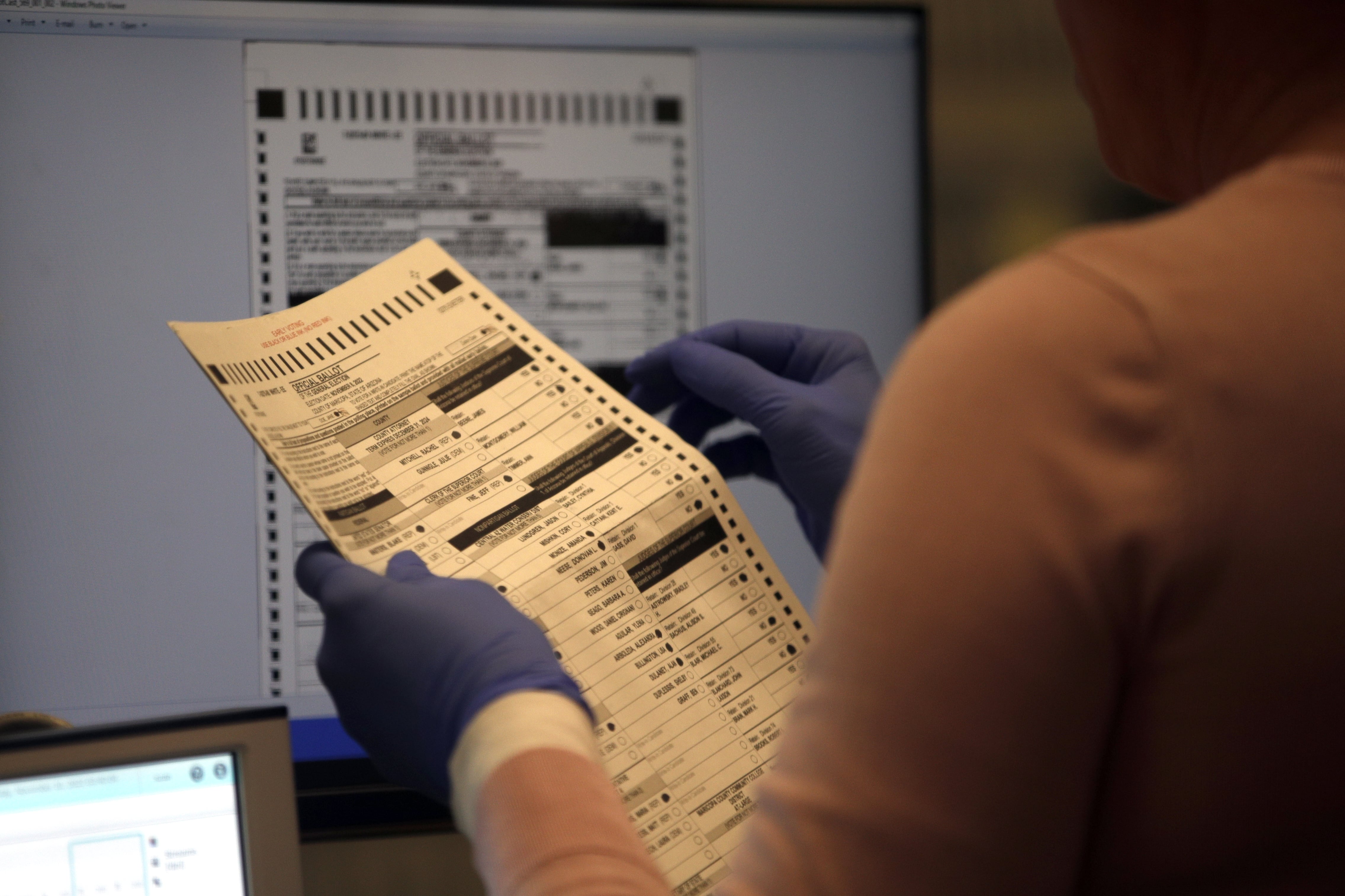 Person wearing glove holds ballot
