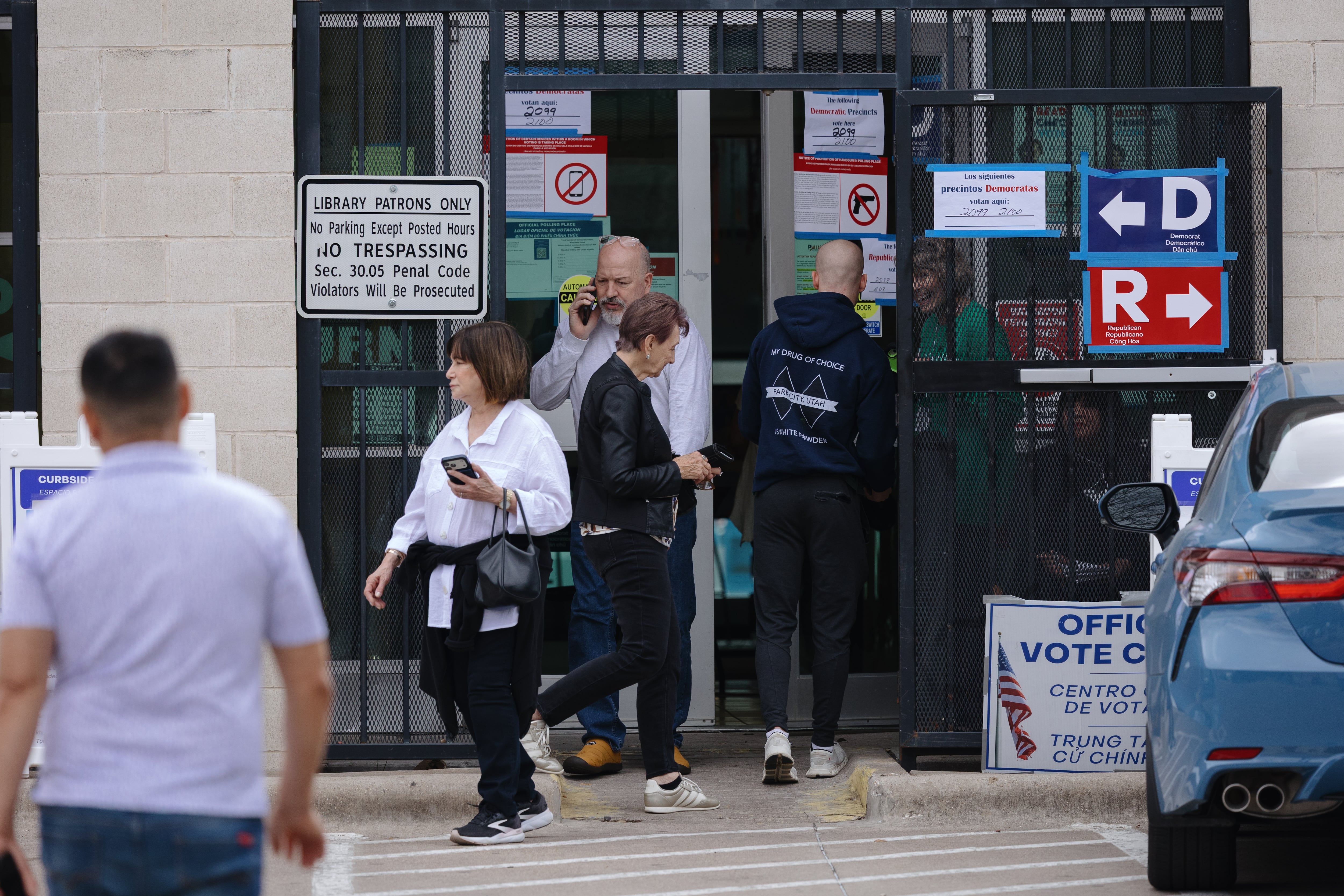 People in front of a library building with a sign that says Offical voting center