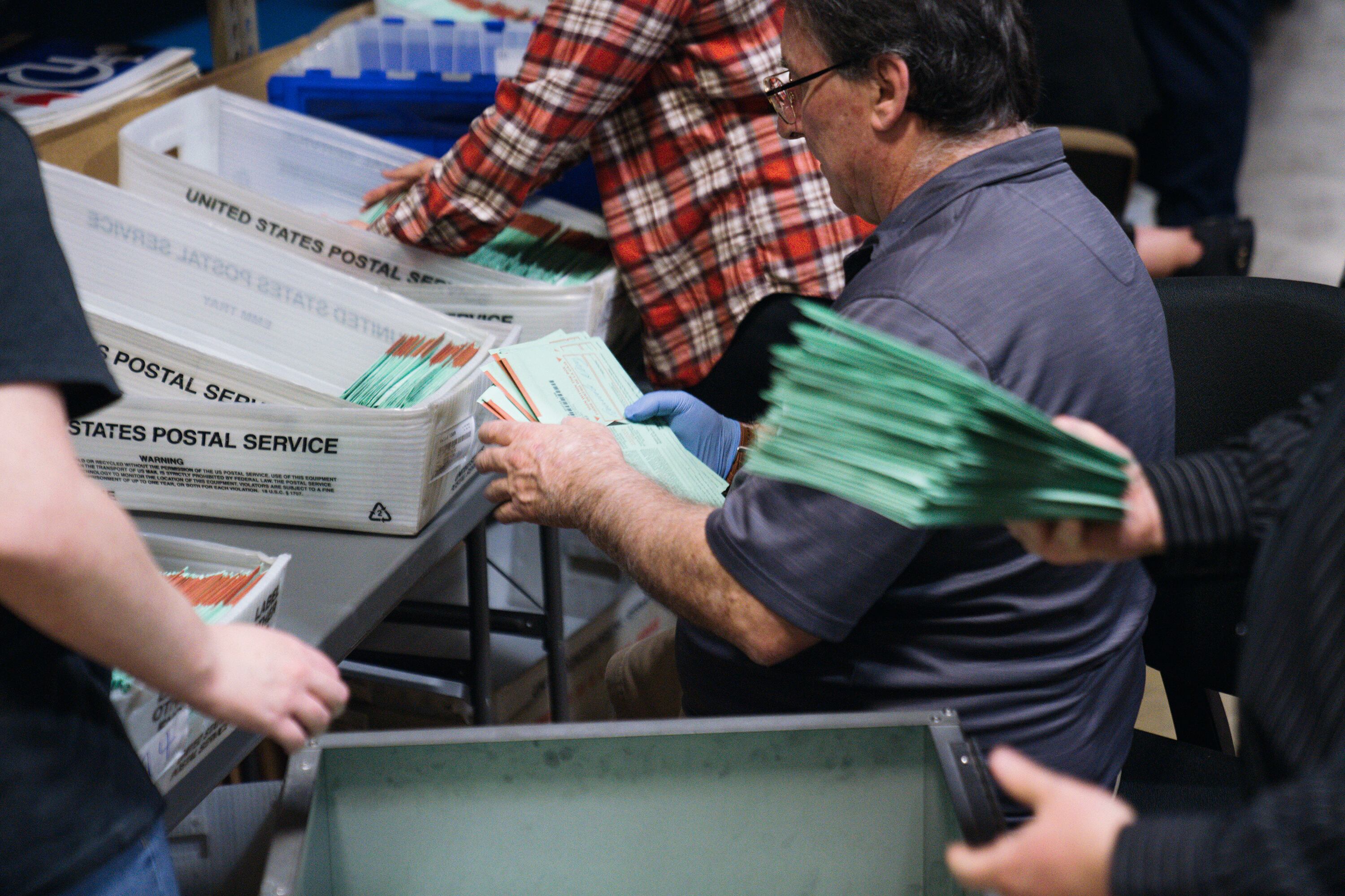 One person is visible in the middle of three others all handling green ballots.