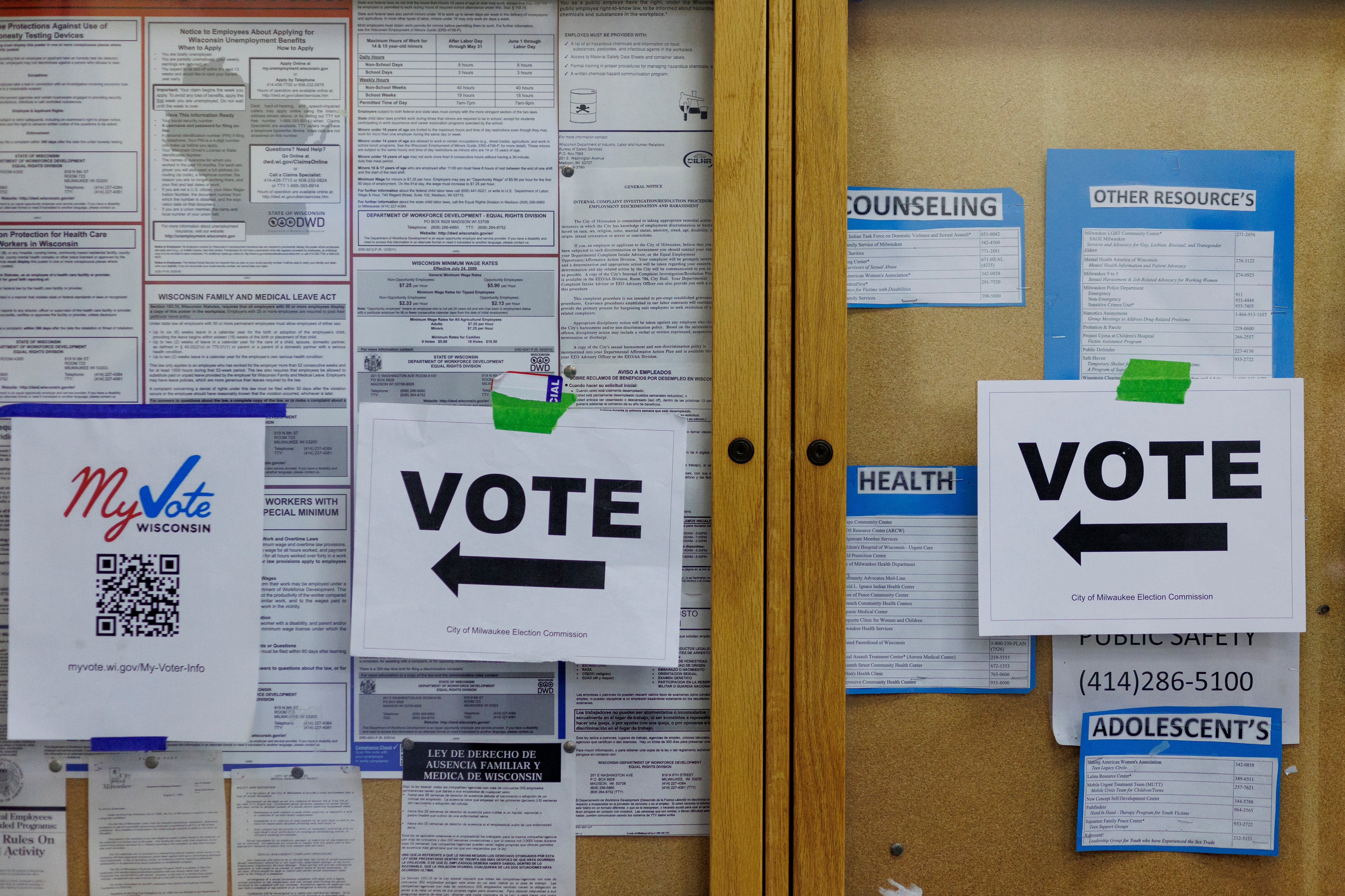 A wall of papers some say "Vote" with an arrow directing foot traffic.