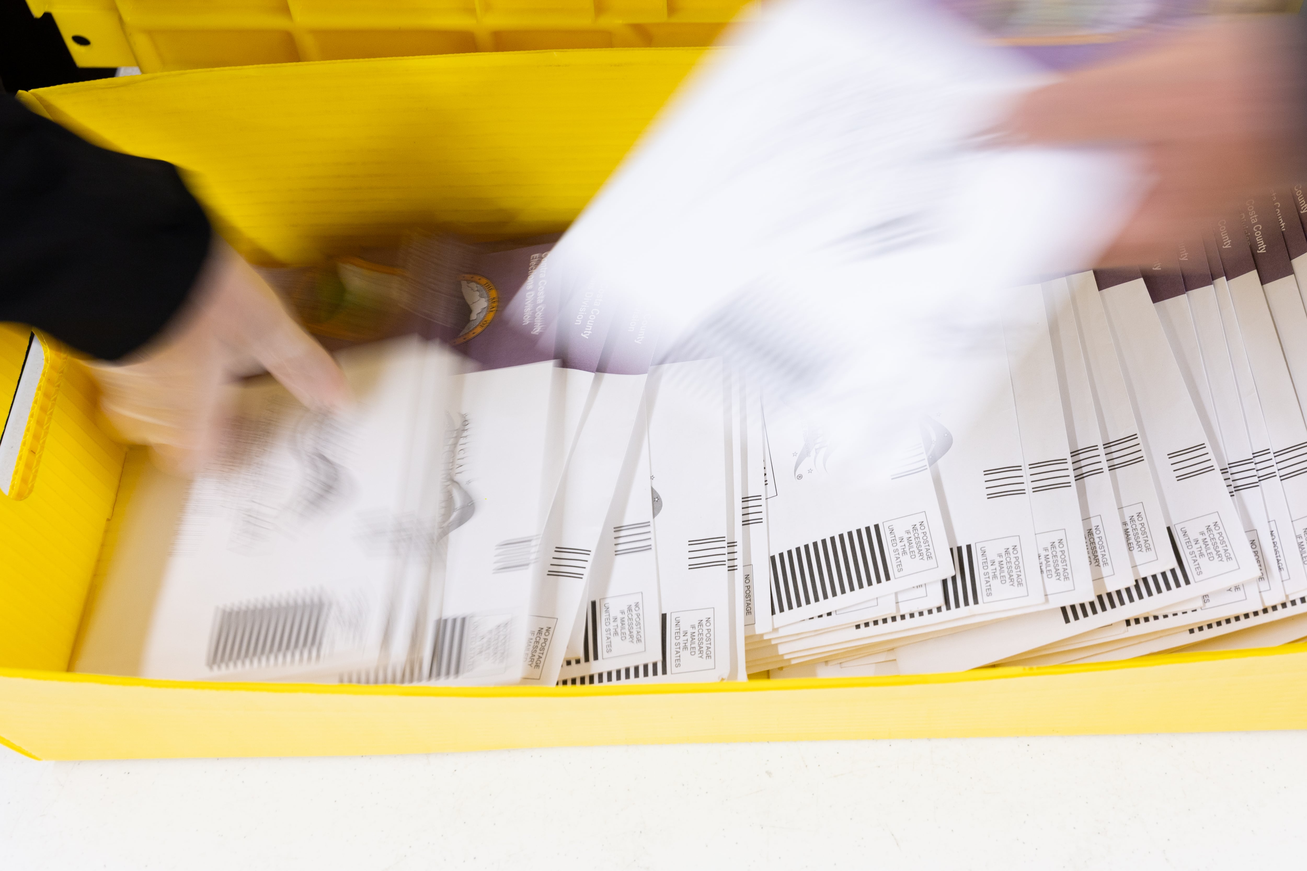 Hands hold ballots that are blurred due to movement.