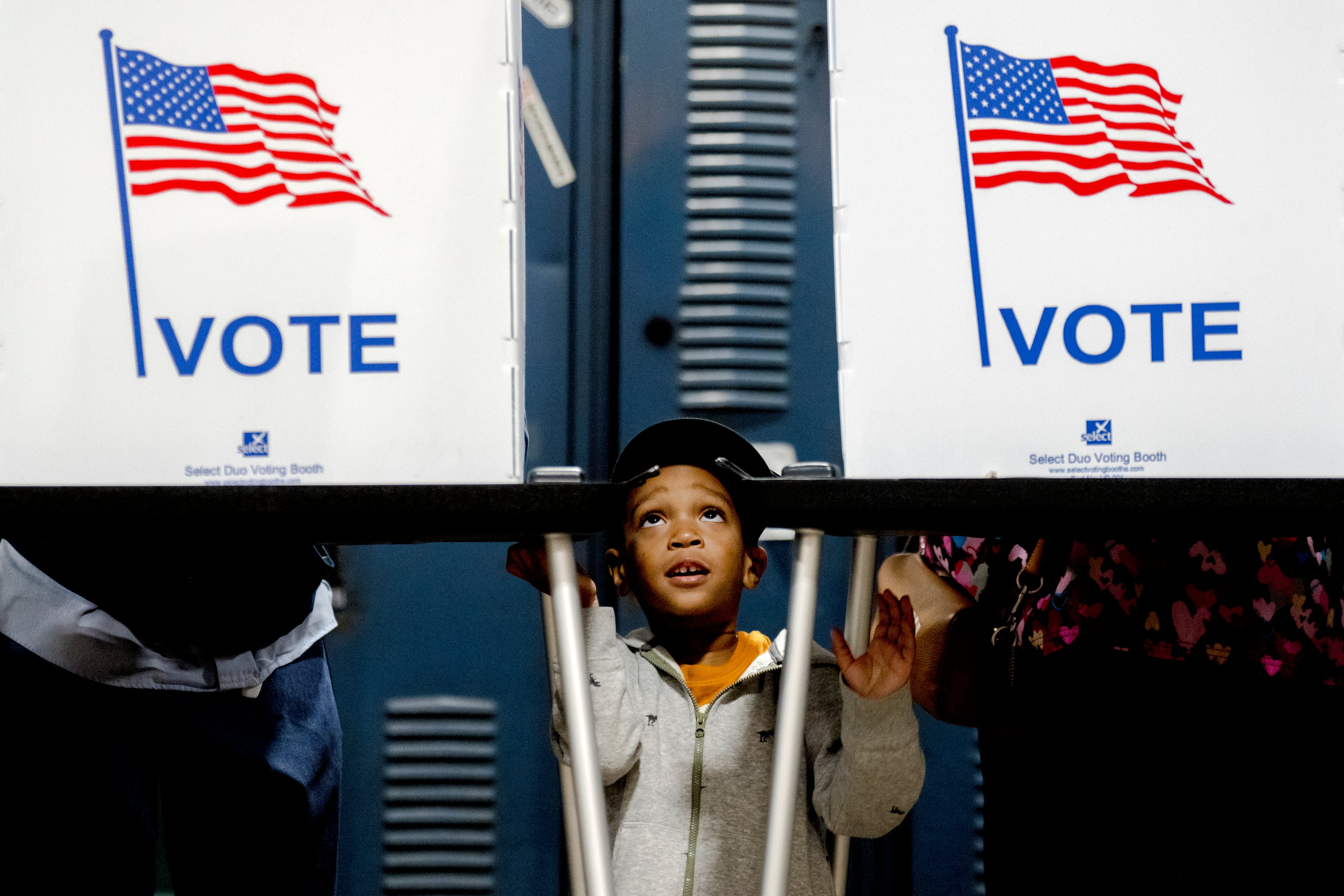 A little boy looks up between two polling machines.