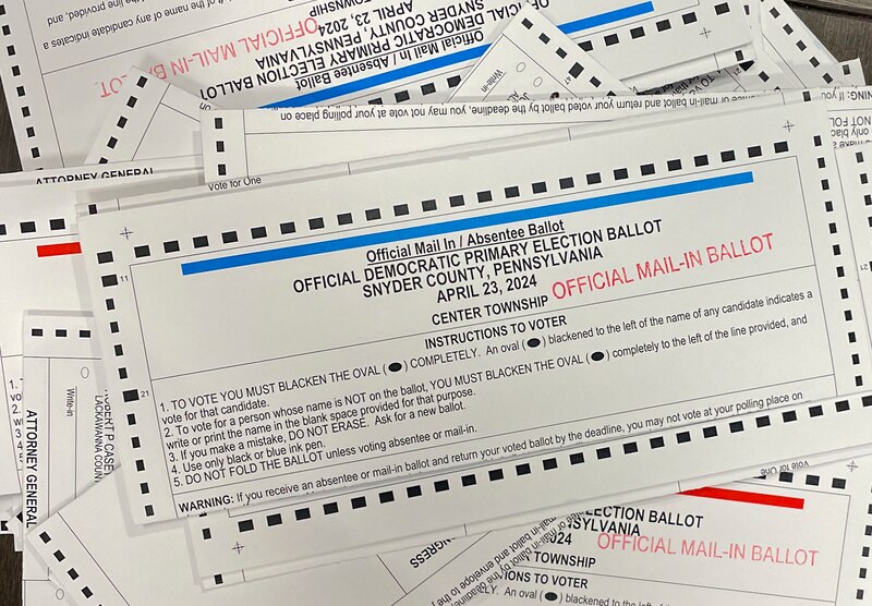 A stack of ballots spread out with white, blue, red and black ink.