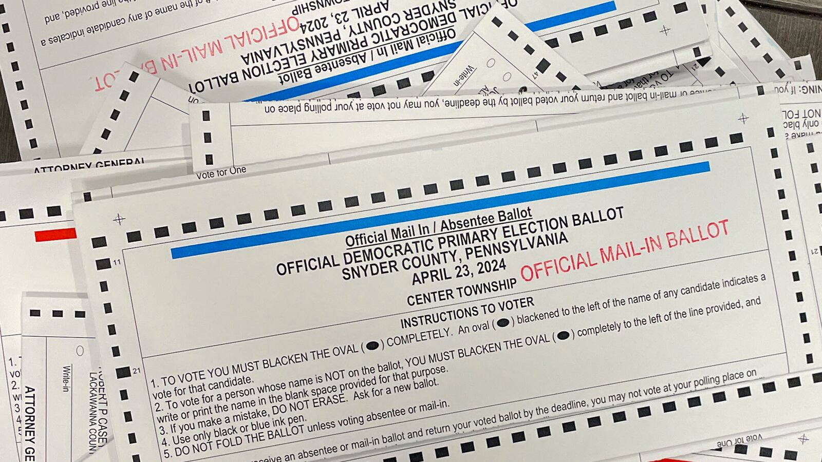 A stack of ballots spread out with white, blue, red and black ink.