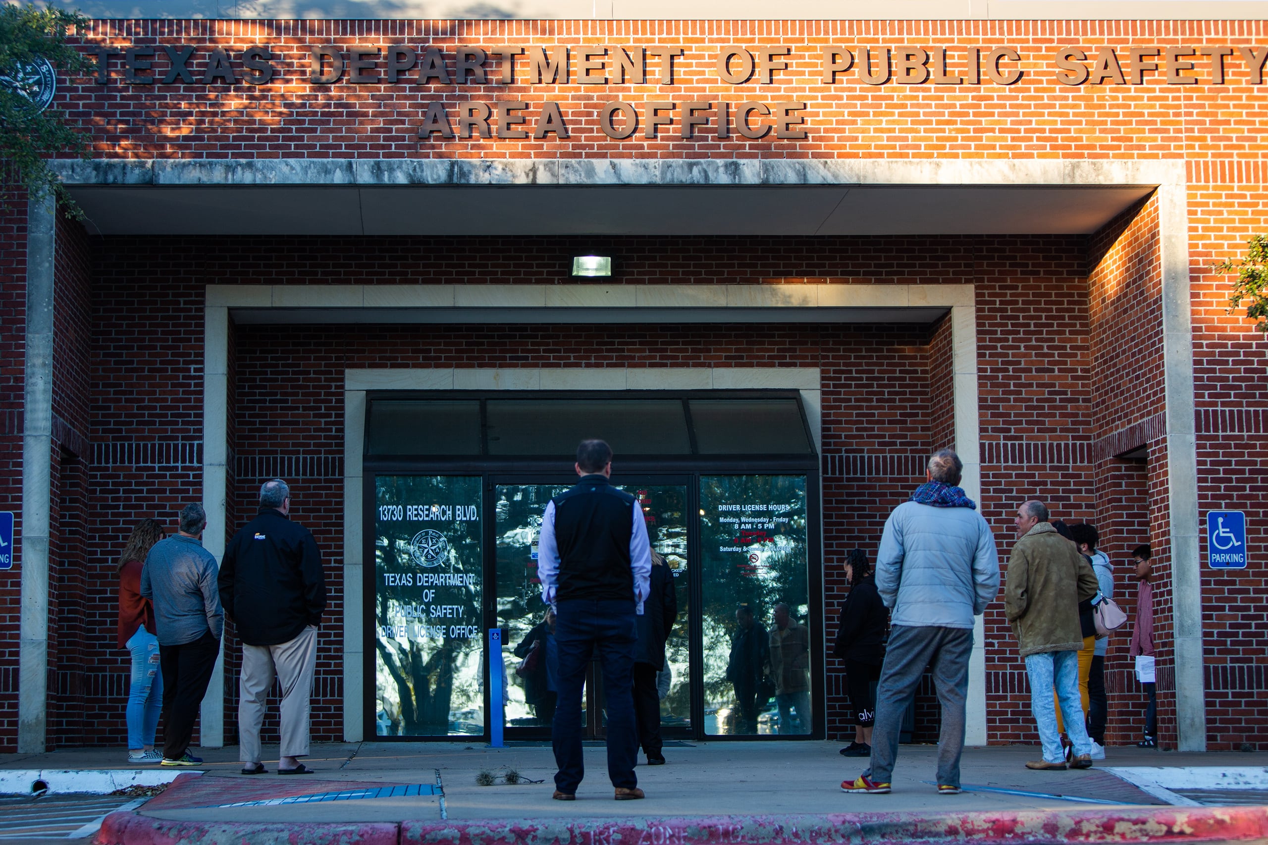 People line up outside a brick building
