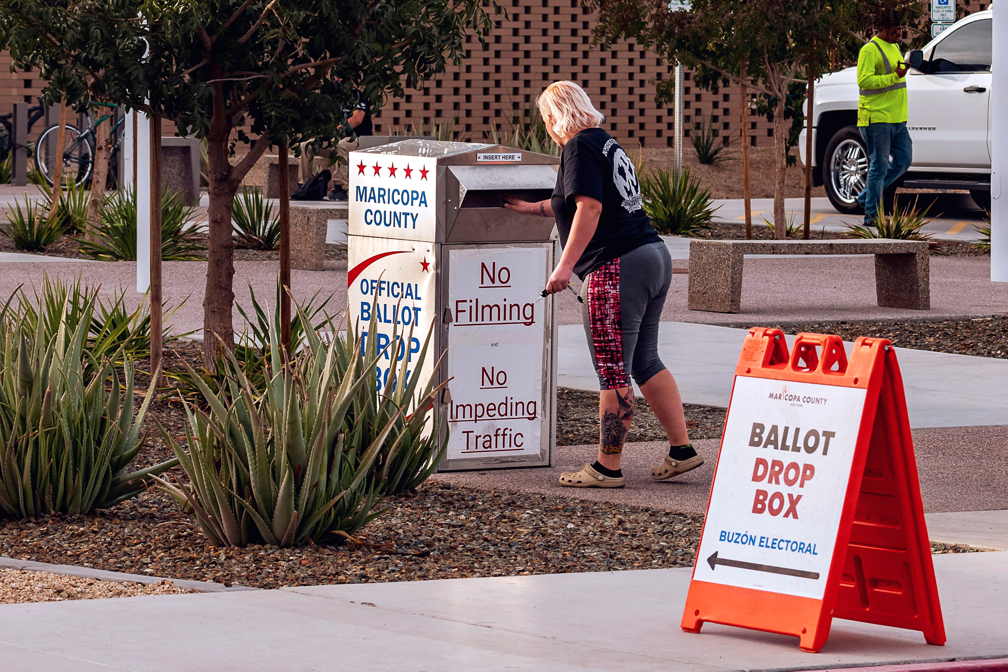 A woman in a black t-shirt drops something in a box.