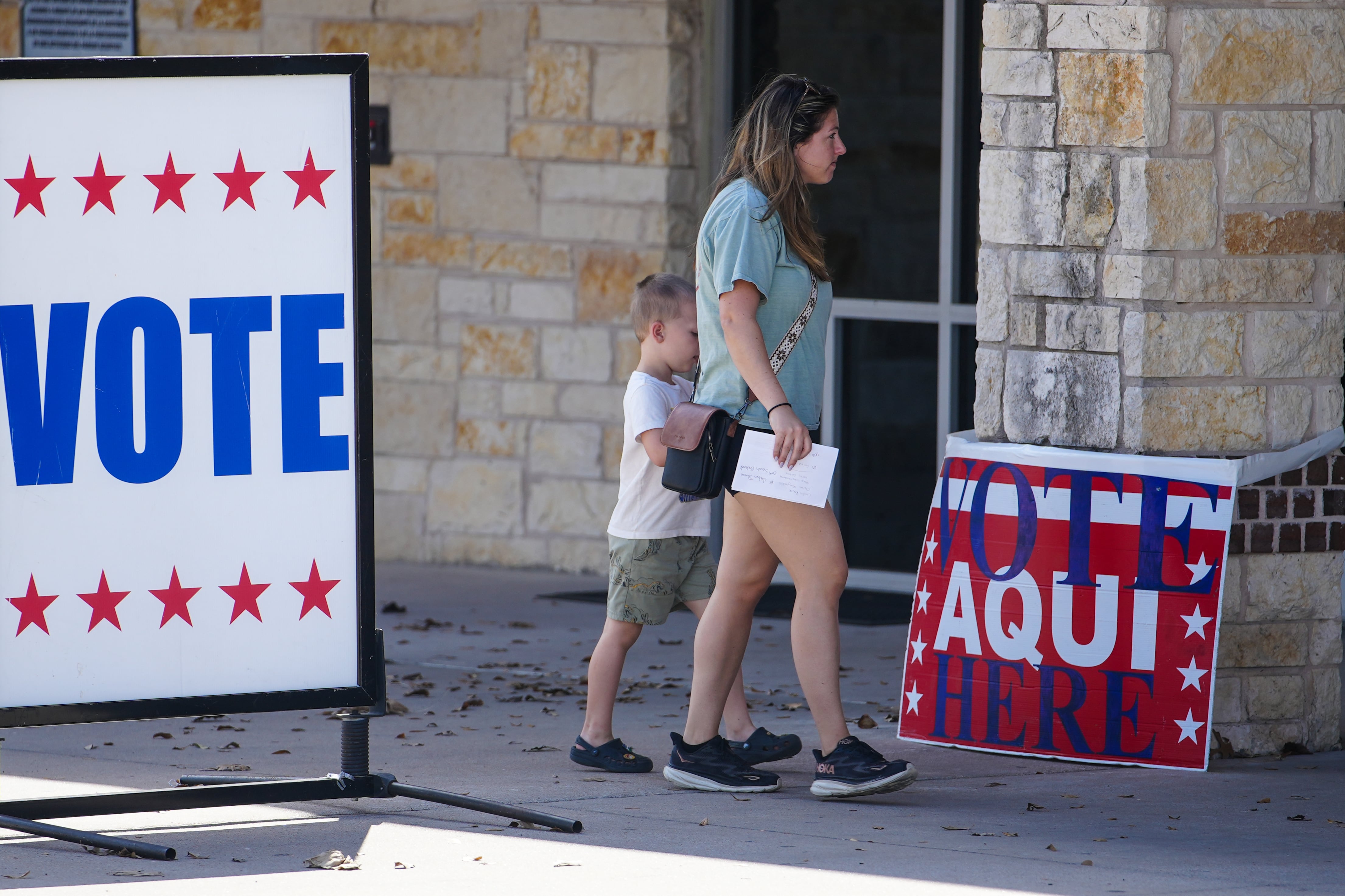 A woman and a child walk between voting signs.