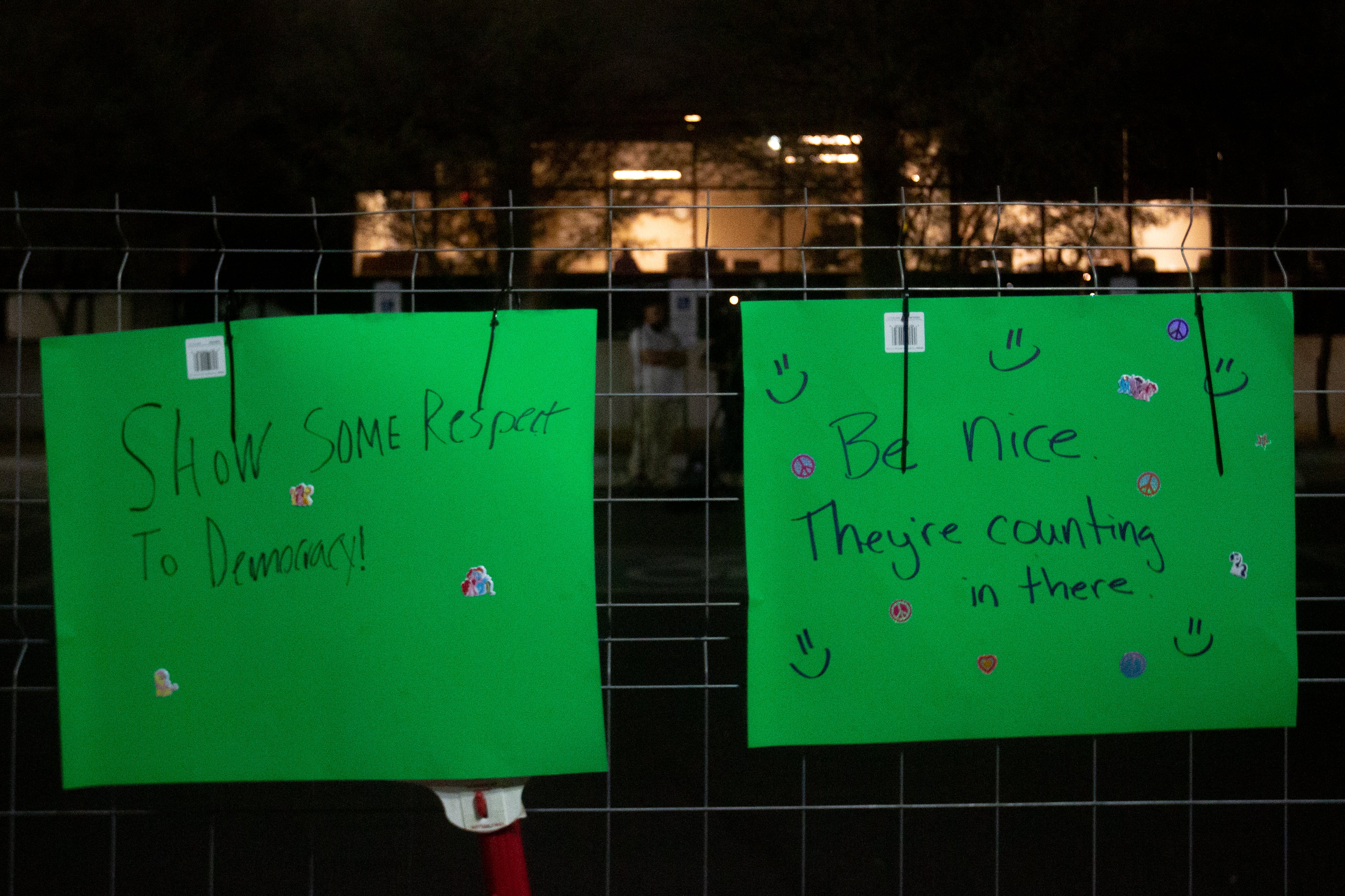 two green signs posted on fence
