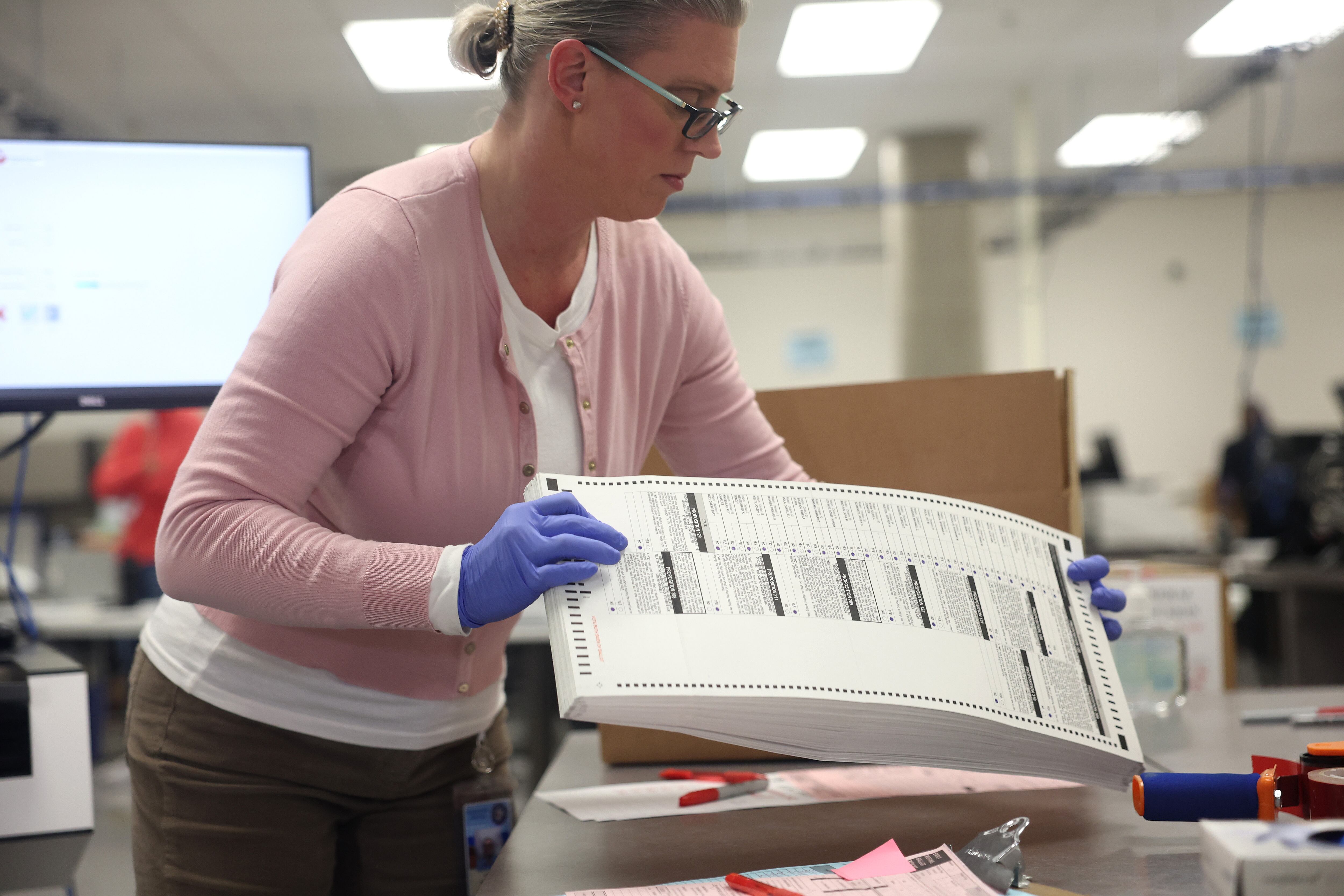 woman with blue gloves holds ballot