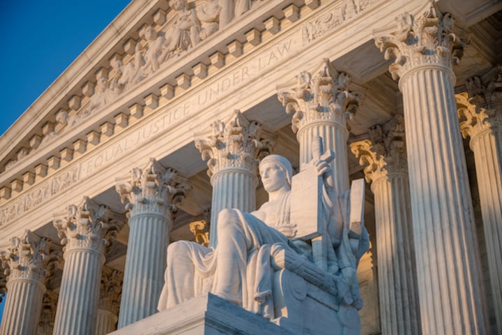 A statue in the foreground of the Supreme Court facade.