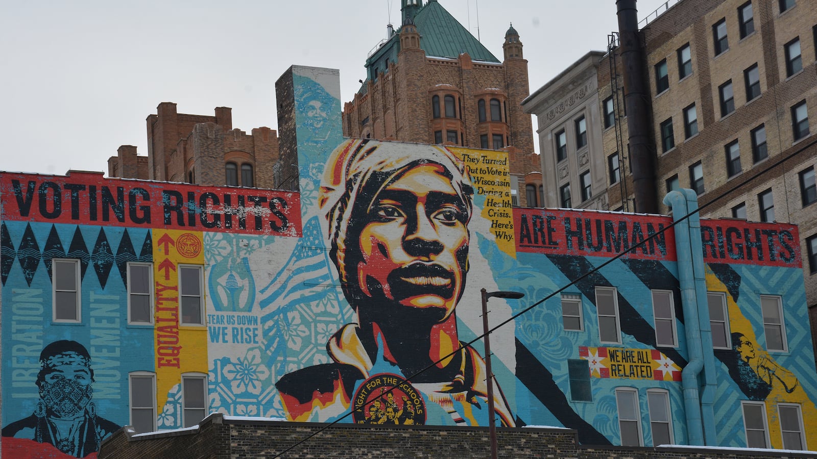 A photograph of a mural on the side of a large building with a skyline in the background.