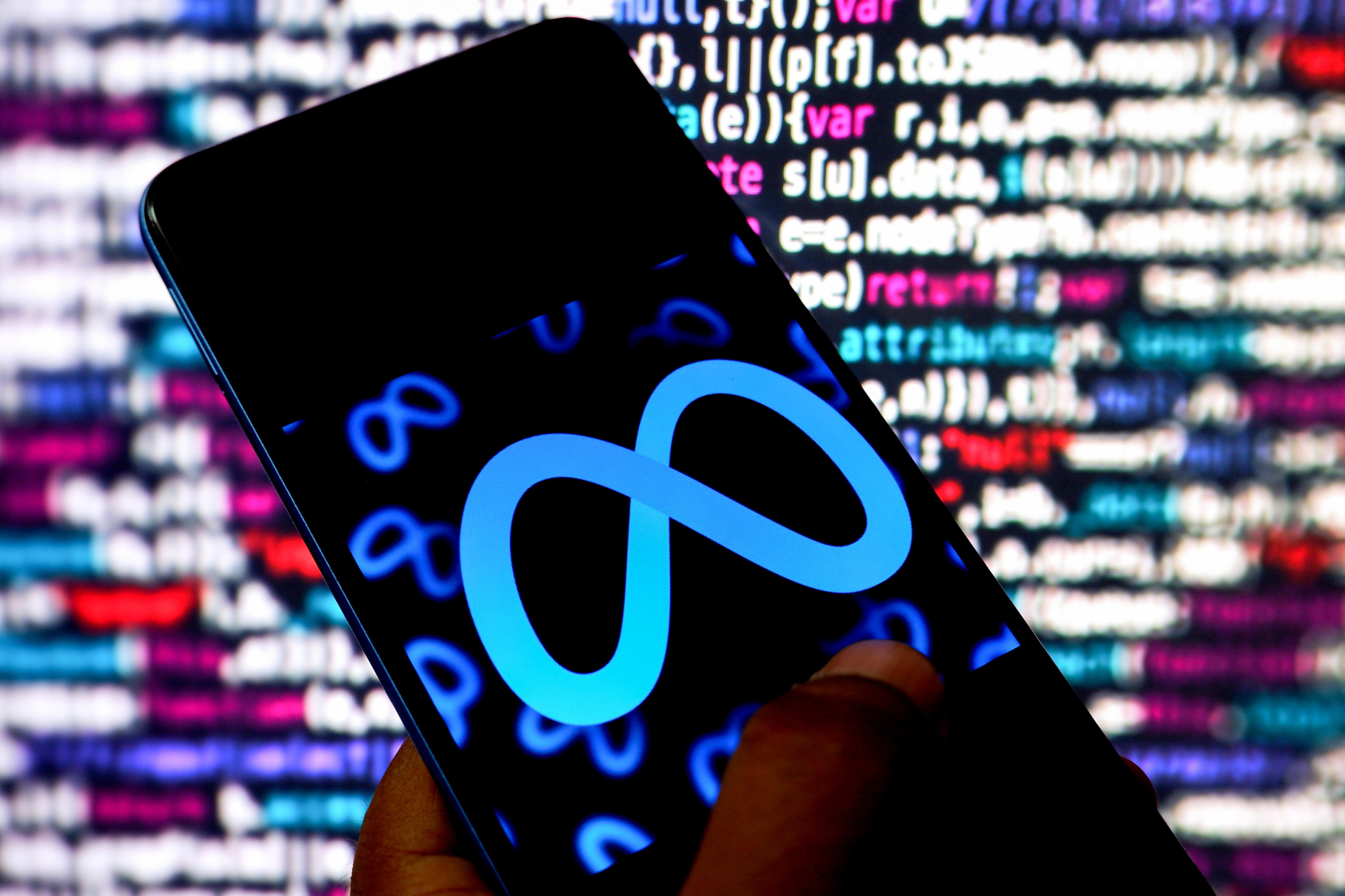 A smartphone displays the Meta logo against lines of code projected in the background.