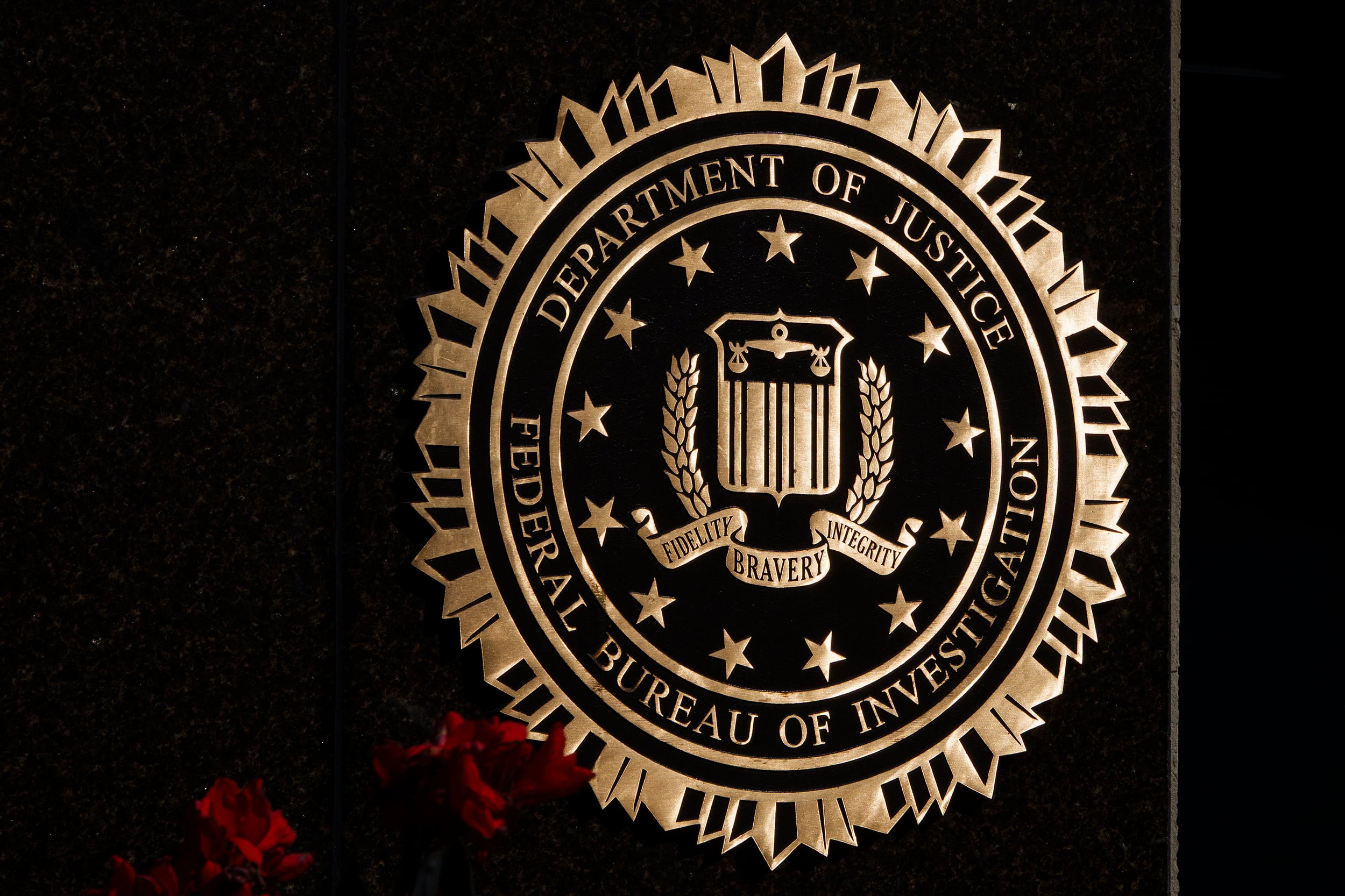 The FBI logo in gold on a dark stone wall.