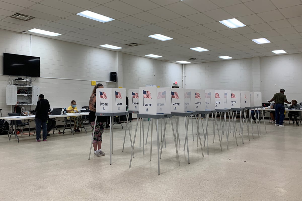 Two rows of voting booths line the middle of a bright, tile-floor room