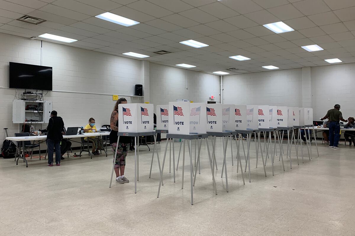 Two rows of voting booths line the middle of a bright, tile-floor room