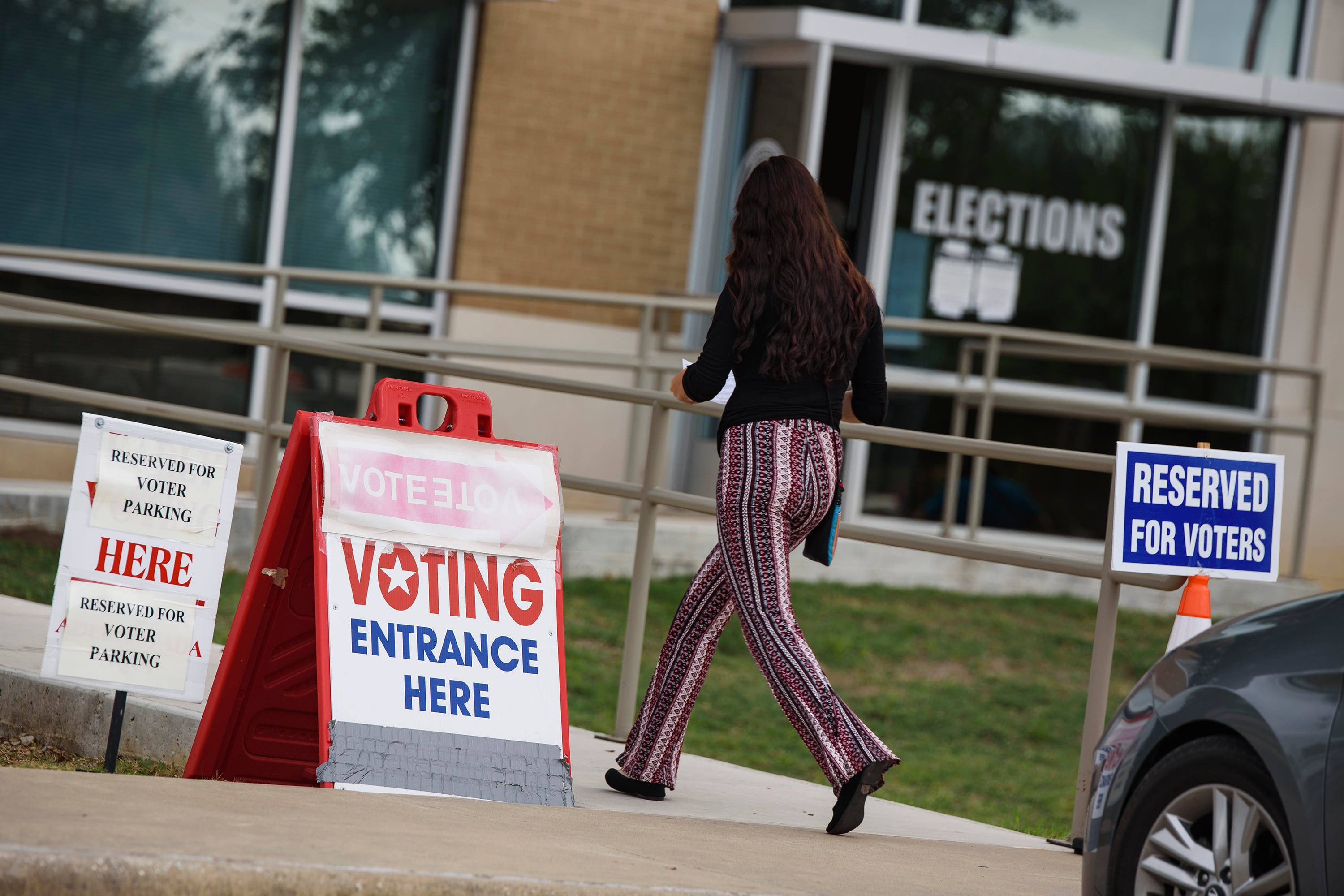 A woman walks toward a building near a sign that says ‘voting entrance’