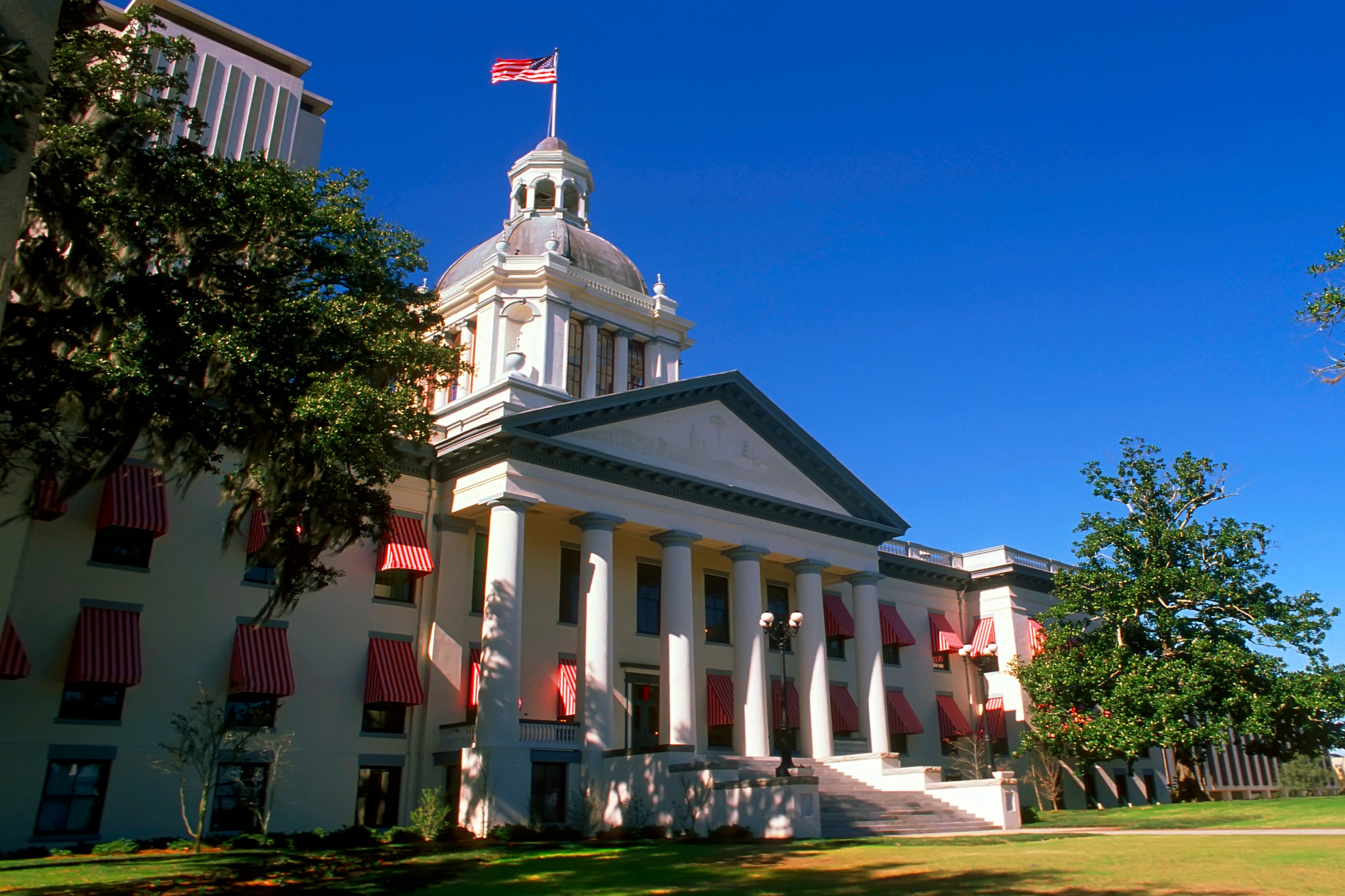 A flag flies atop a white columned building.