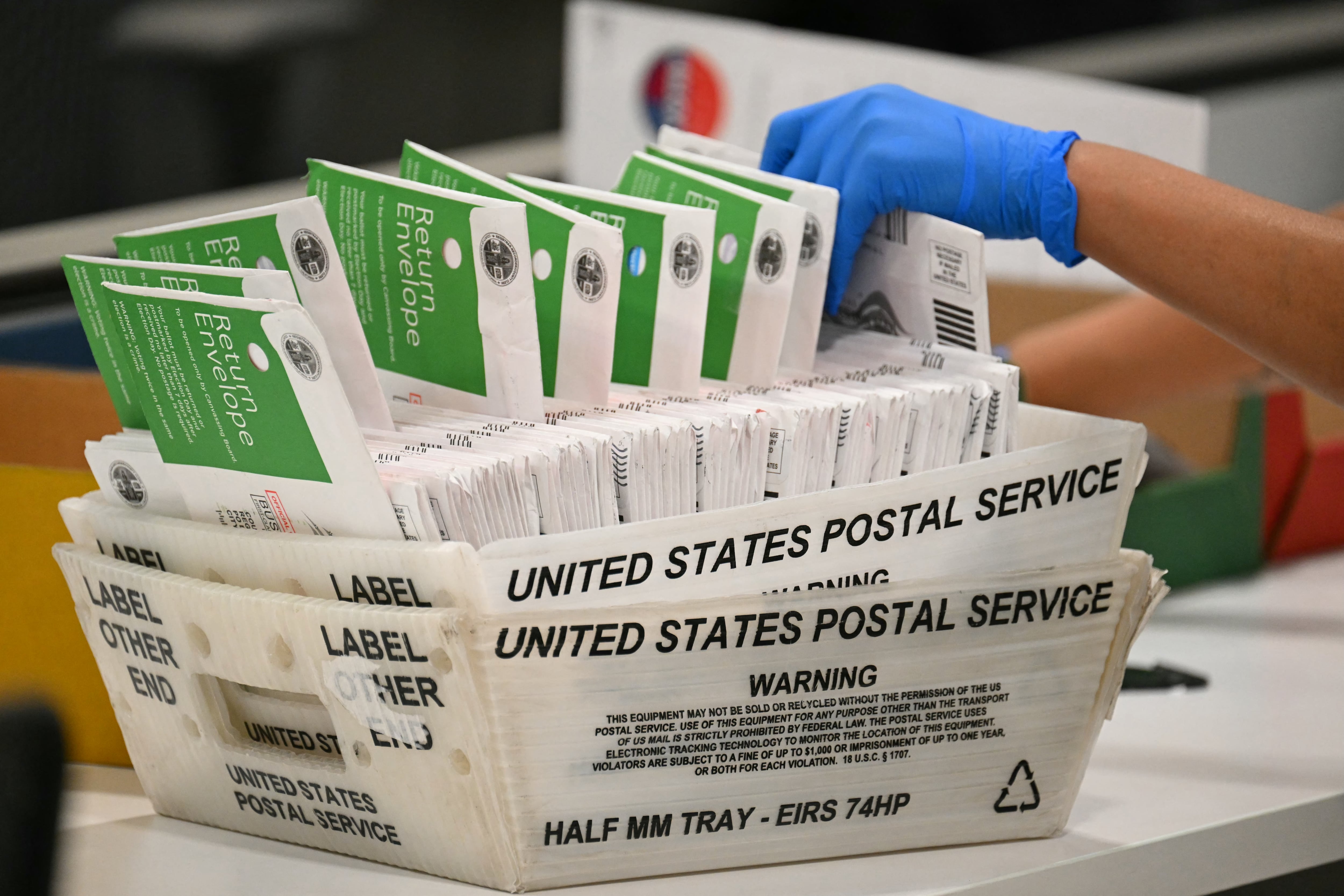 A gloved hand sorts through ballots.