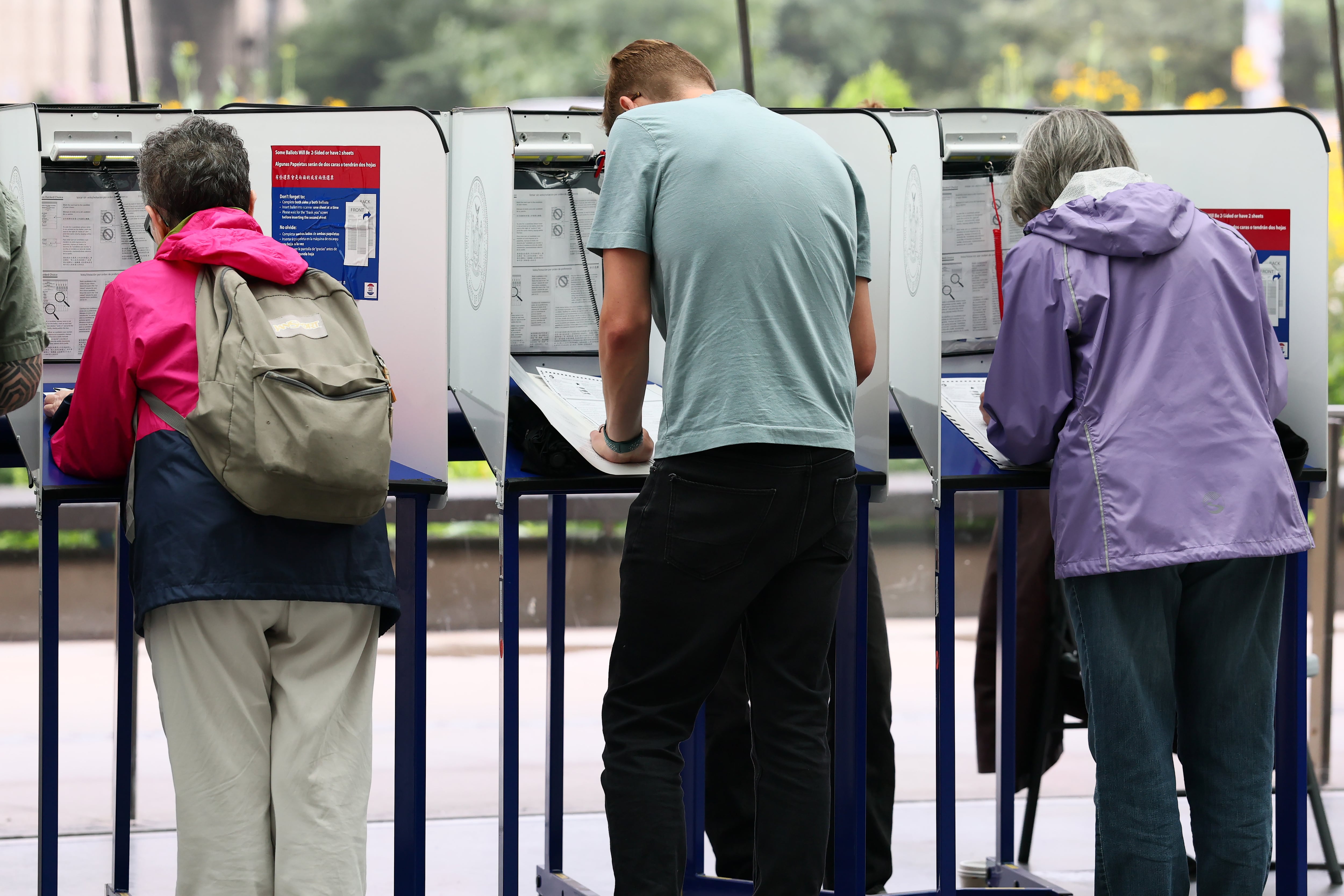 Three people vote at voting machines.
