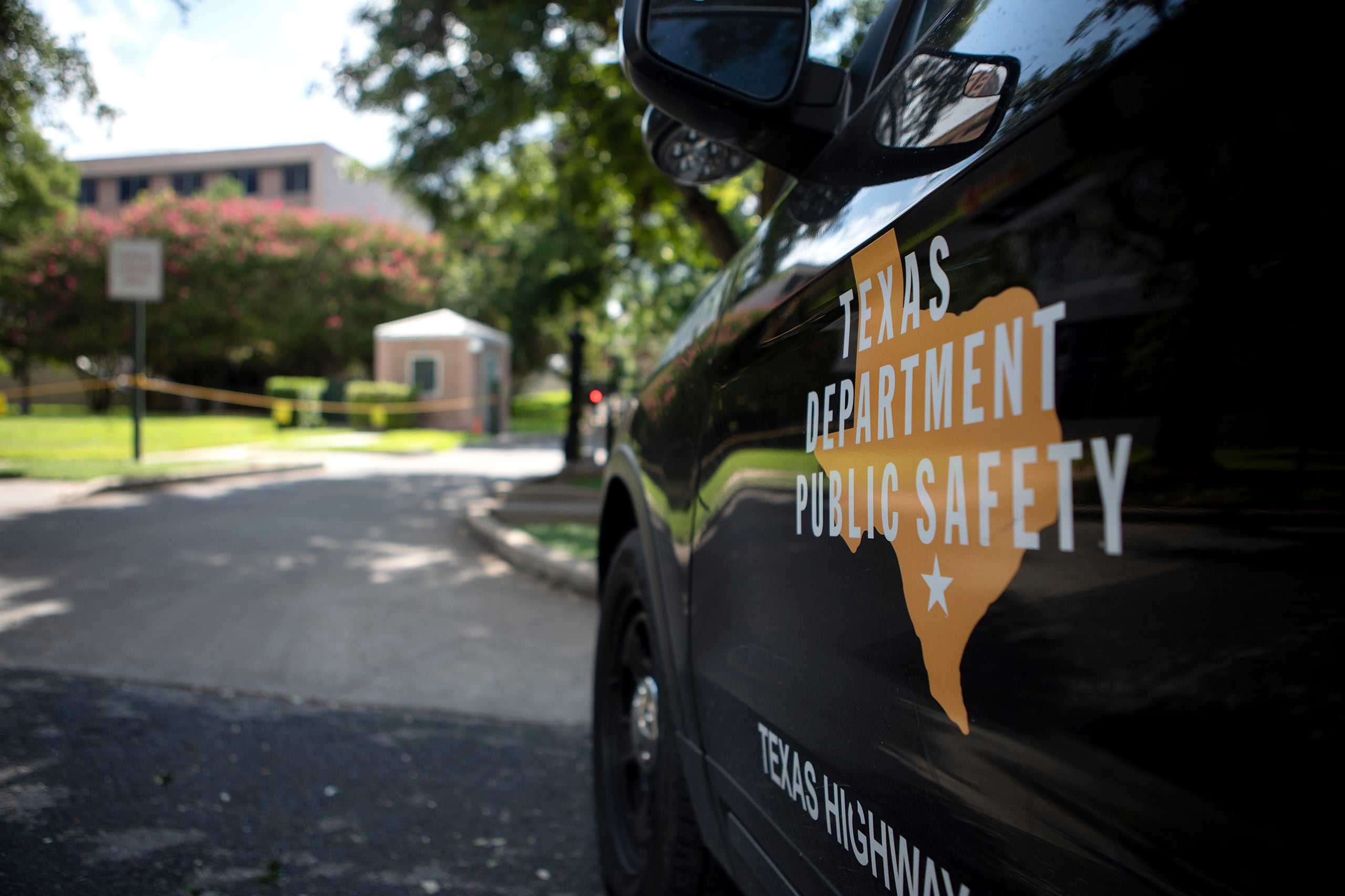 A photograph of a public safety car with a logo outside of a buiding.