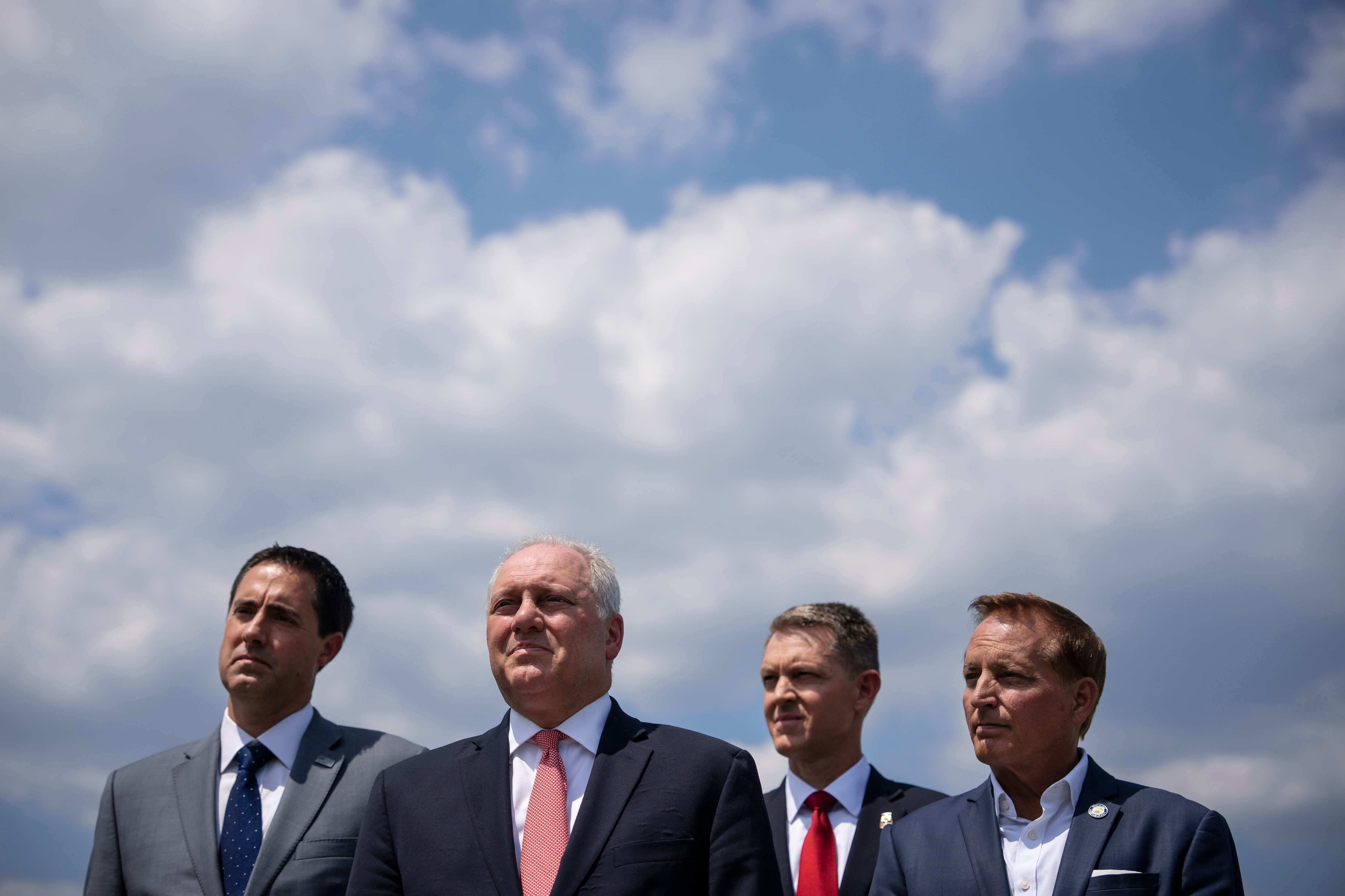 Four men in suits standing before a cloudy sky