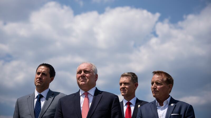 Four men in suits standing before a cloudy sky