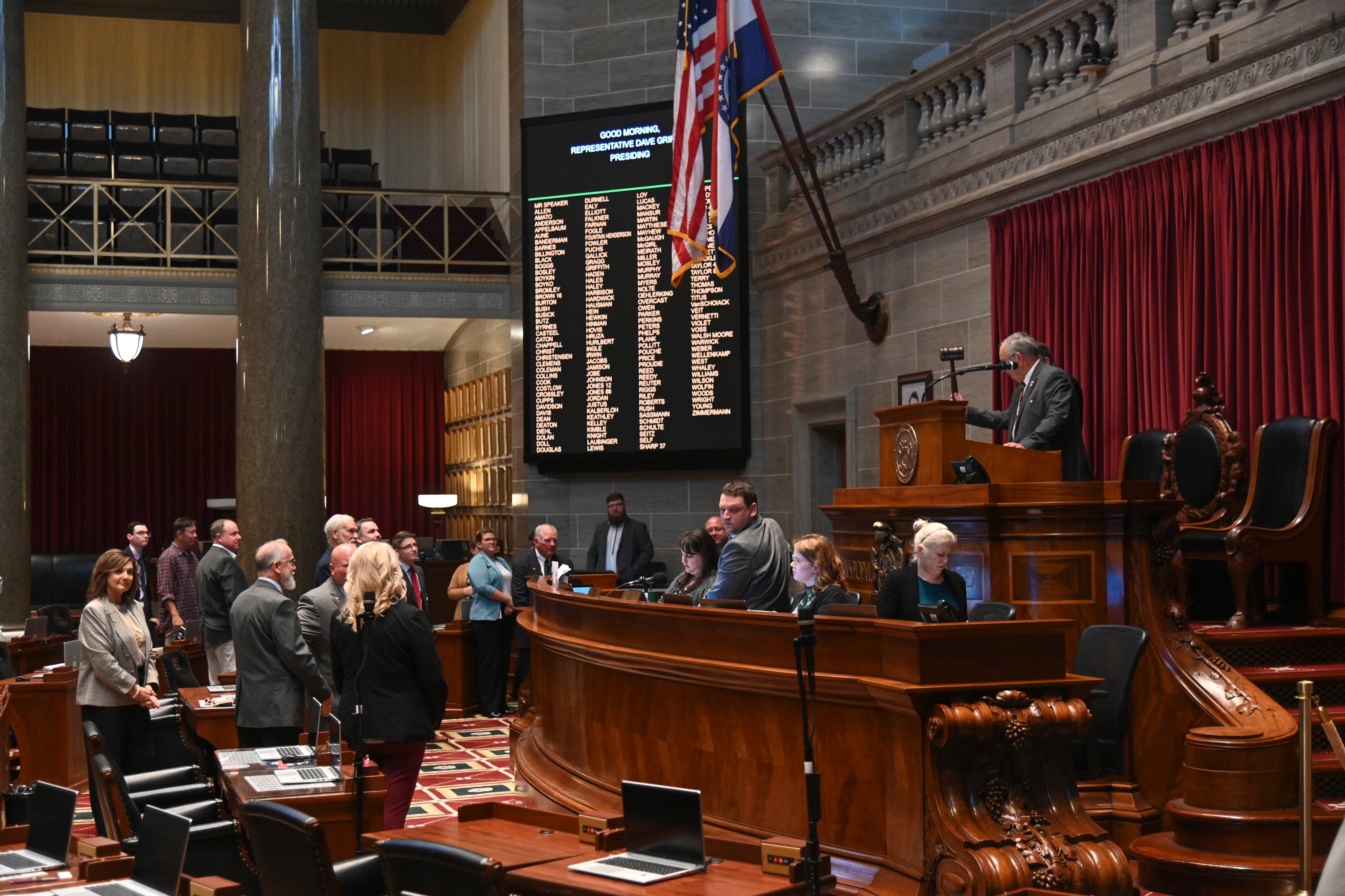 Men and women stand near a large podium in an official-looking room.