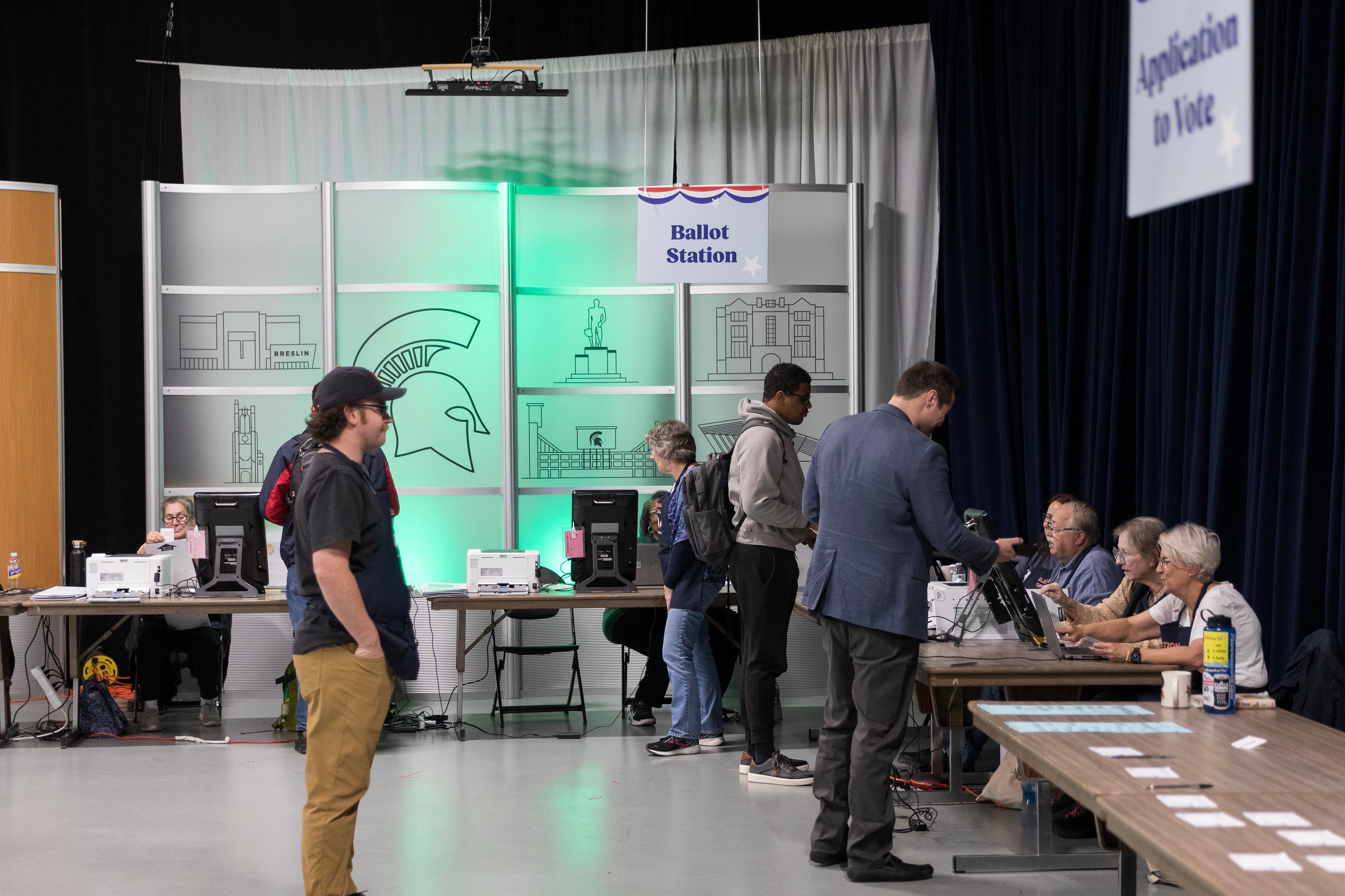 People stand around tables in a large room.