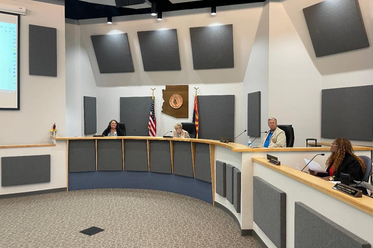 Officials sit at at a dais at the front of a meeting room.