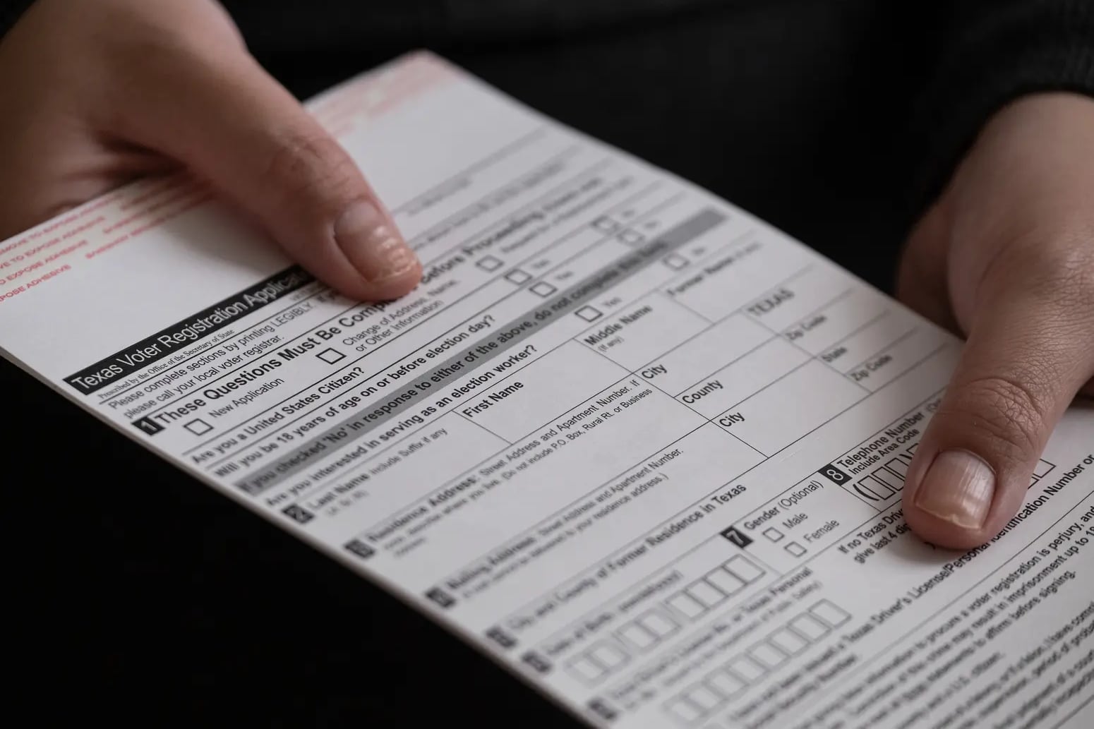 A close up of someone holding a blank voter registration form