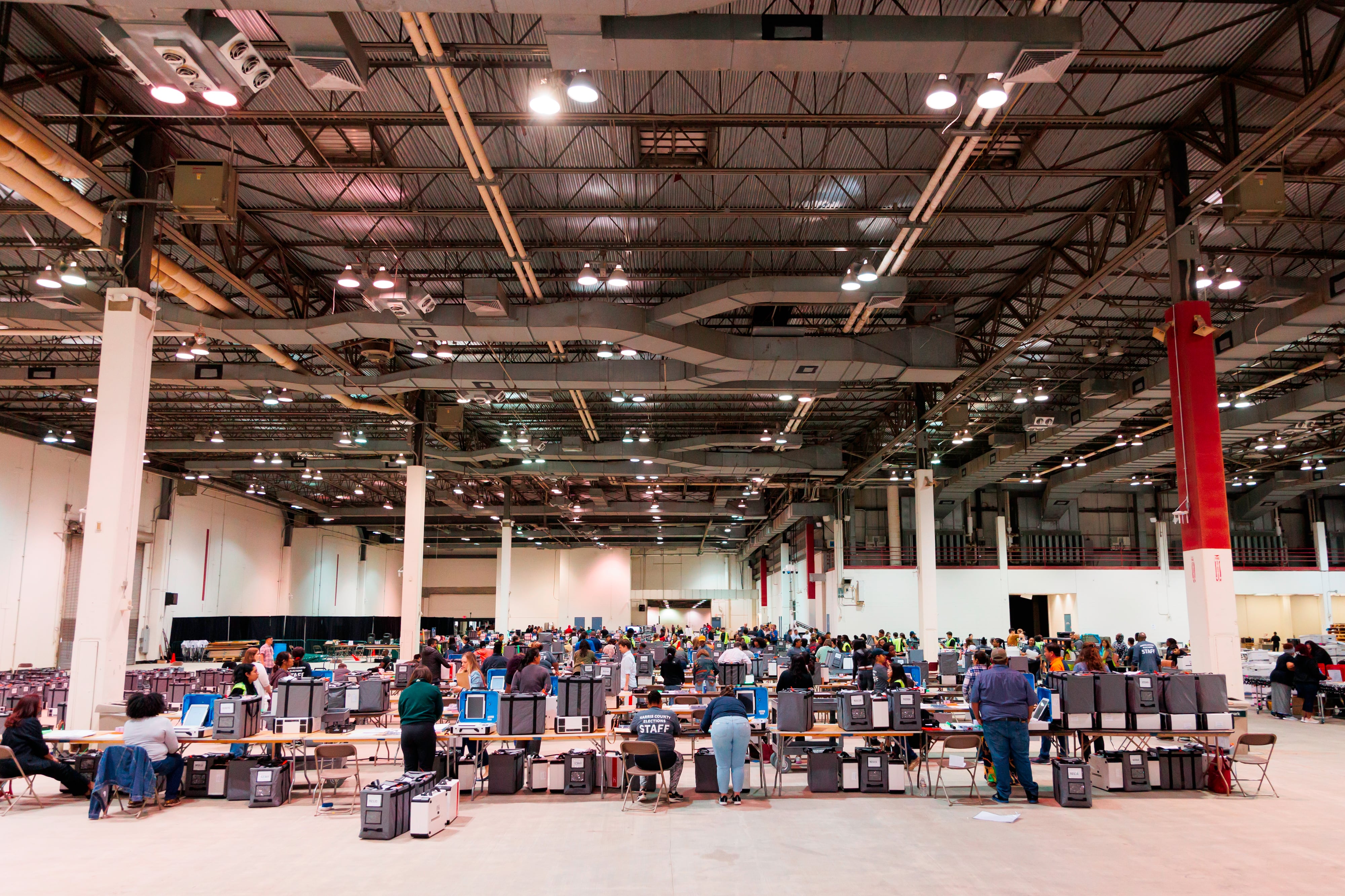 Inside an industrial building, people are seen inspecting machines placed on top of tables