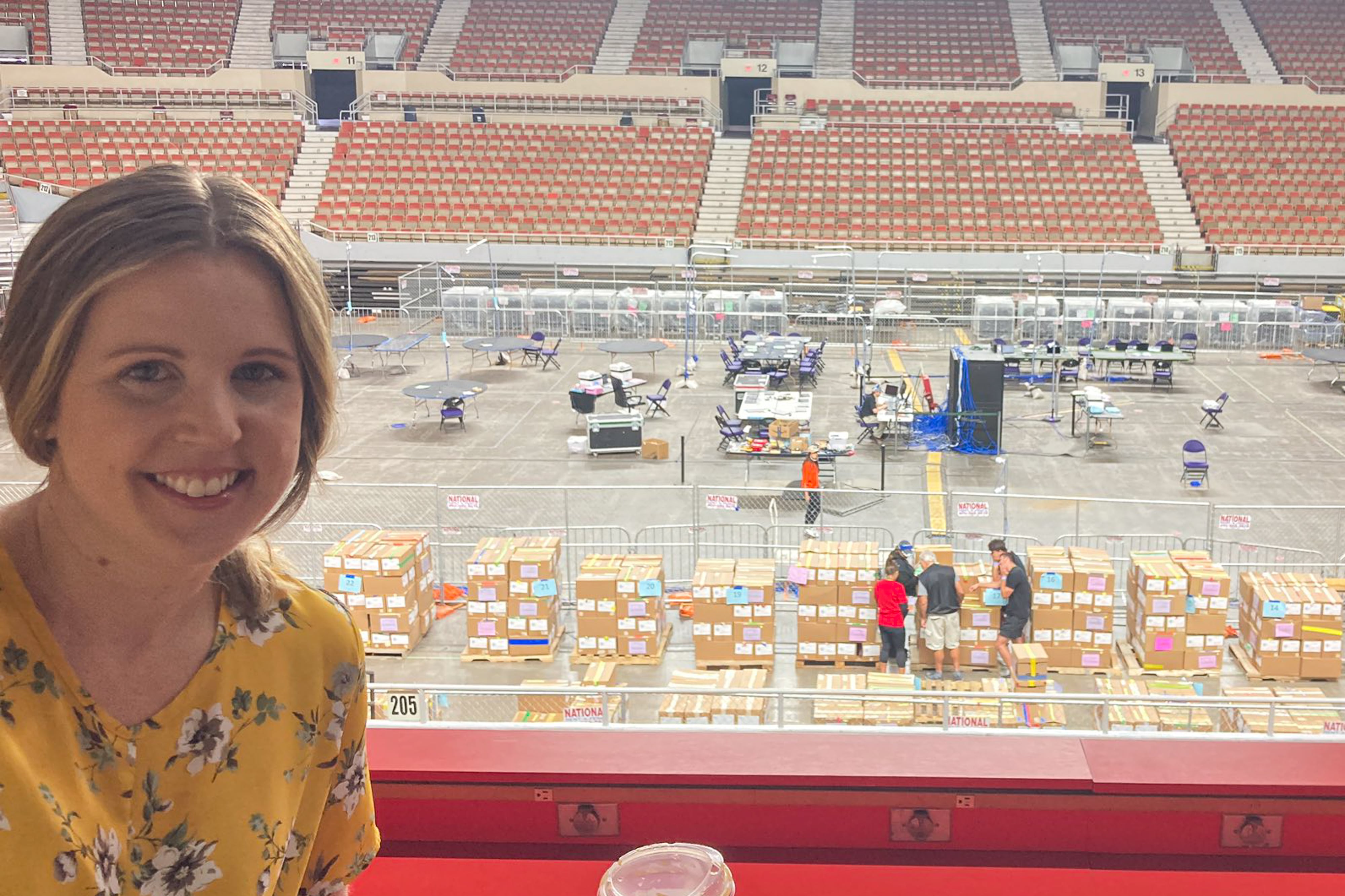 Woman in yellow shirt looks at camera from coliseum stands.