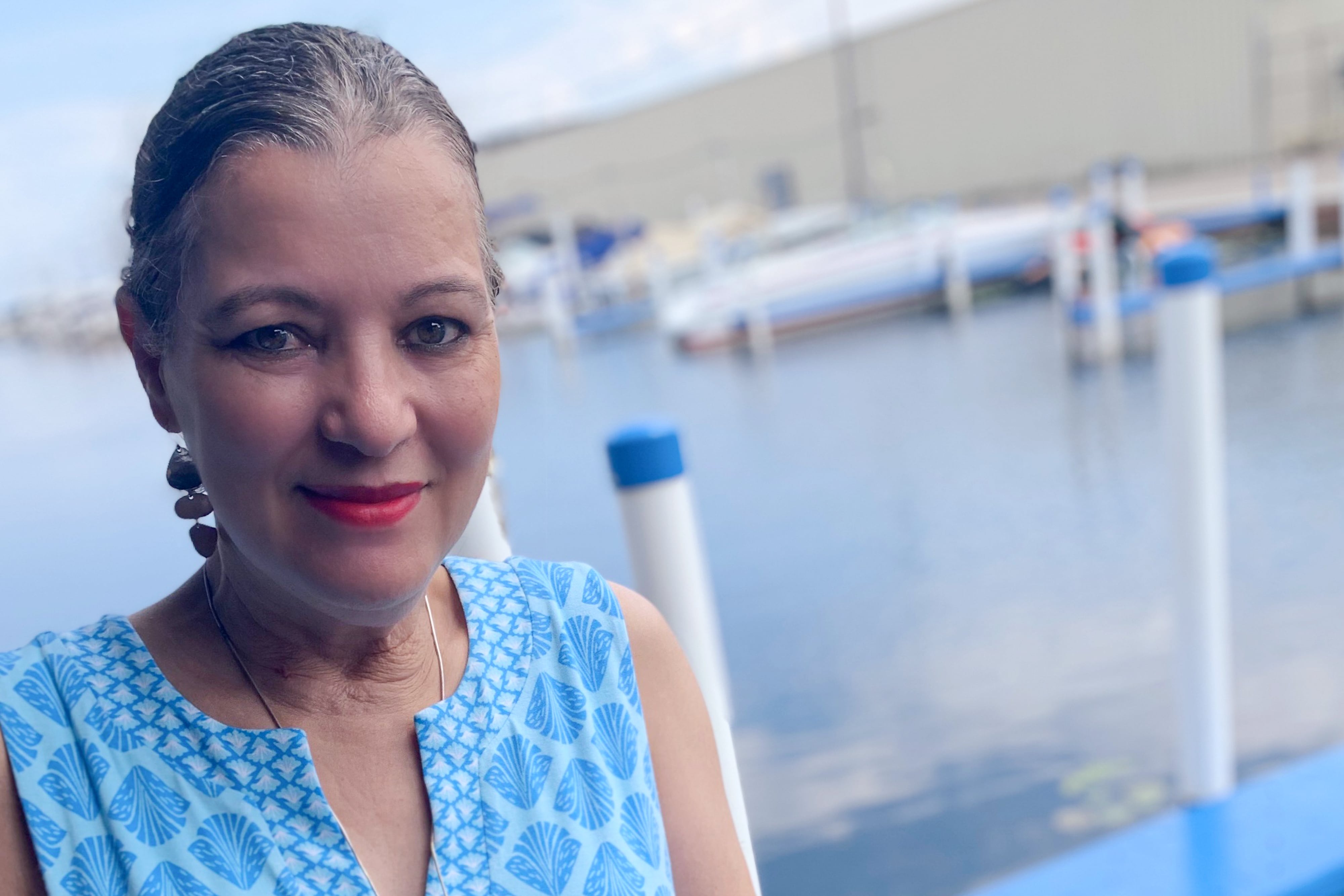 A woman in a blue dress standing at the edge of a marina