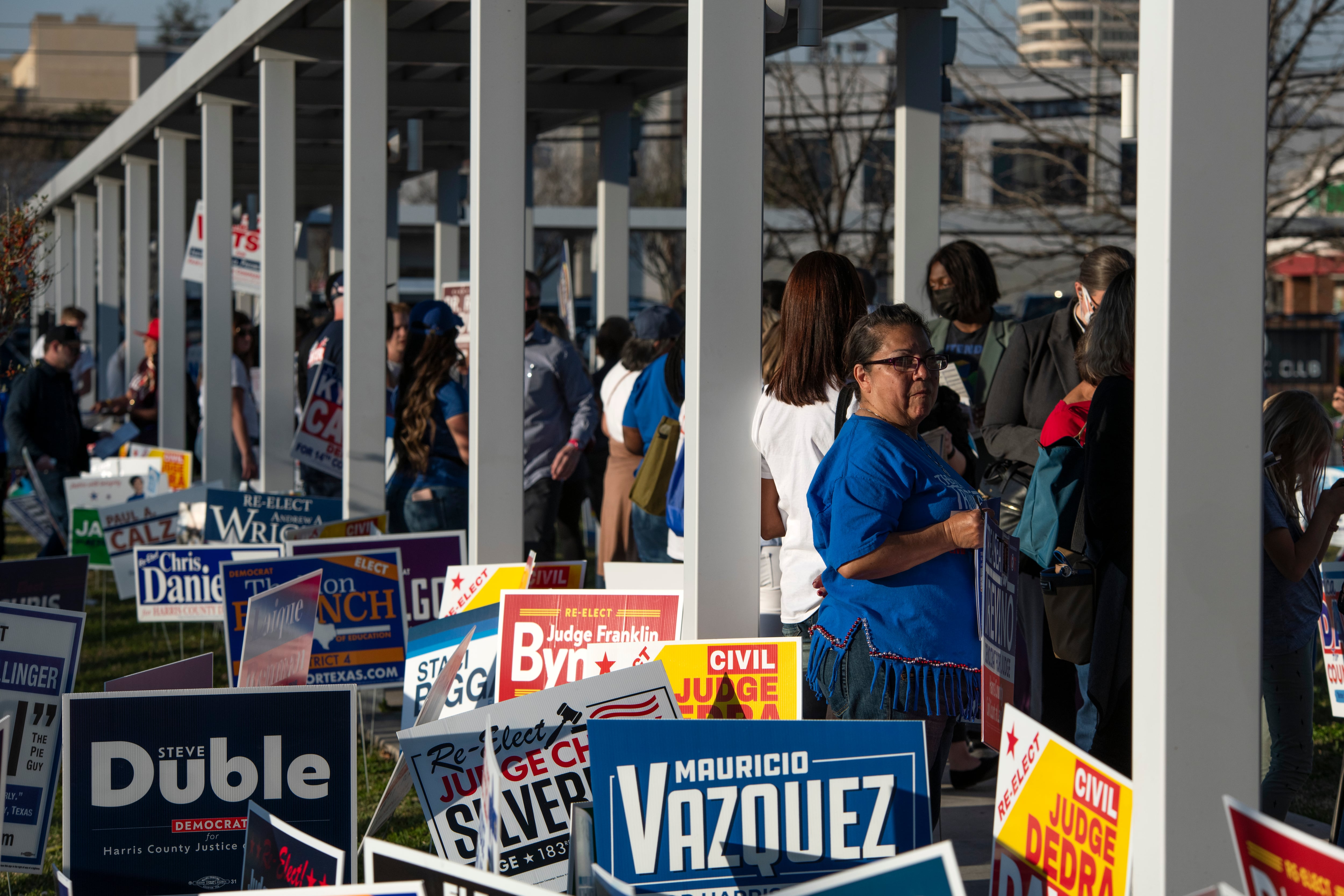 A woman looks over her shoulder in a long line surrounded by campaign signs