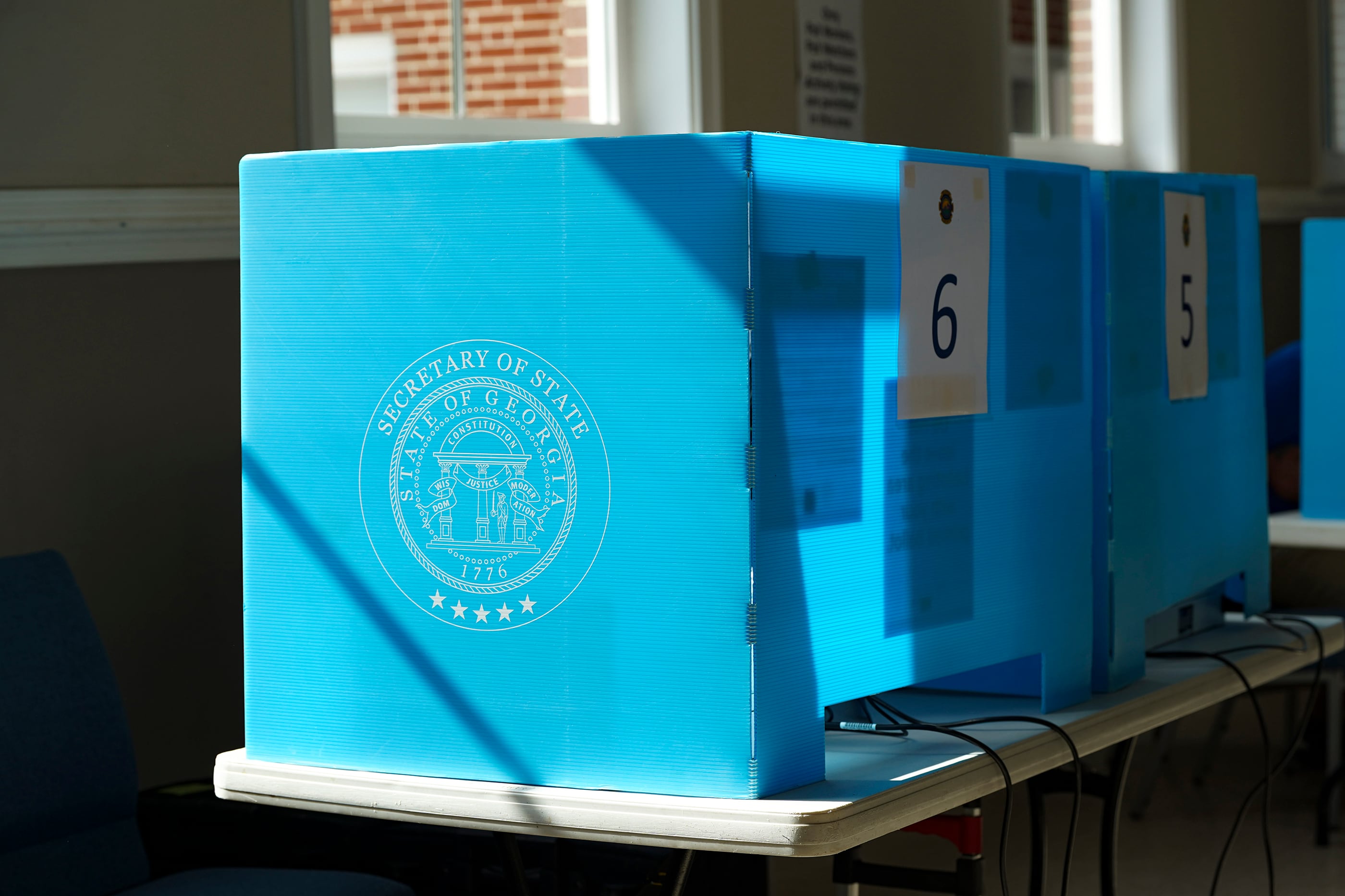 Voter machines surrounded by blue Secretary of State boards in a room on a table.